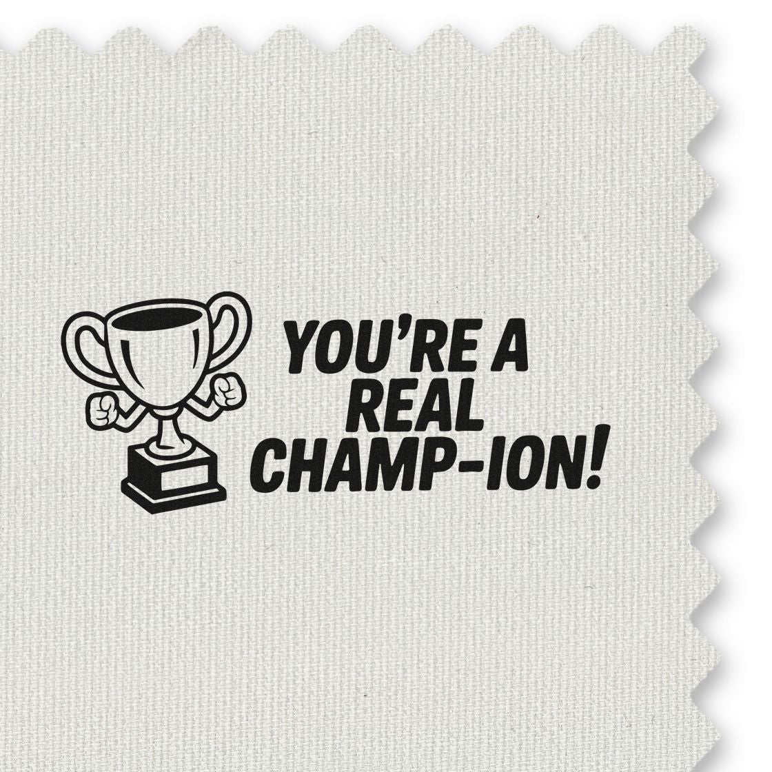 Black trophy stamp seal reading Youre a real champ-ion! on textured white fabric.