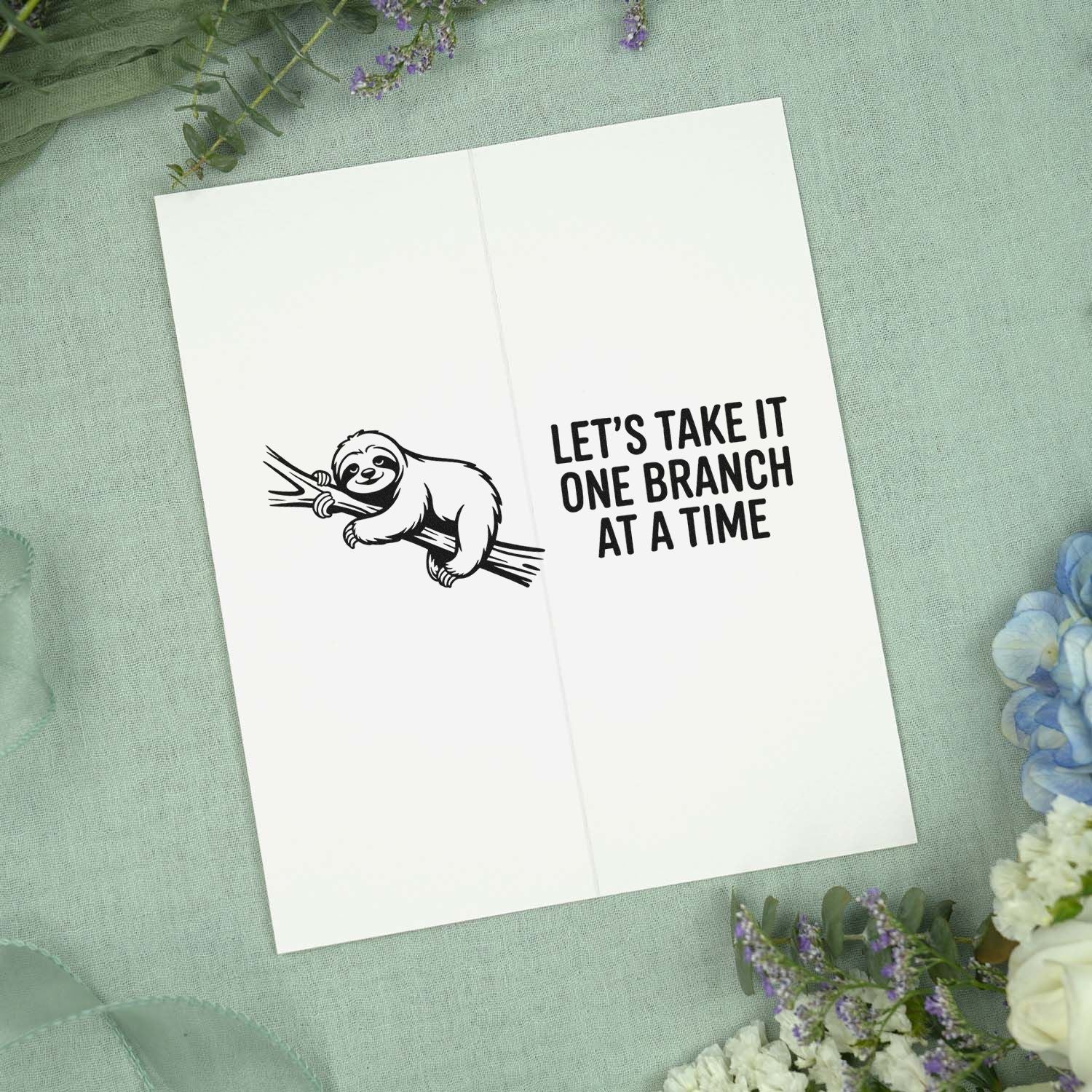 Black sloth stamp and seal on white card, with Lets take it one branch at a time on mint fabric and flowers.