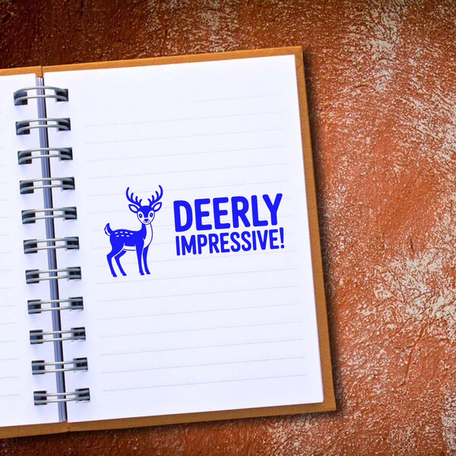 Blue deer stamp with DEERLY IMPRESSIVE! on white notebook page, showcasing custom stamp and seal design.