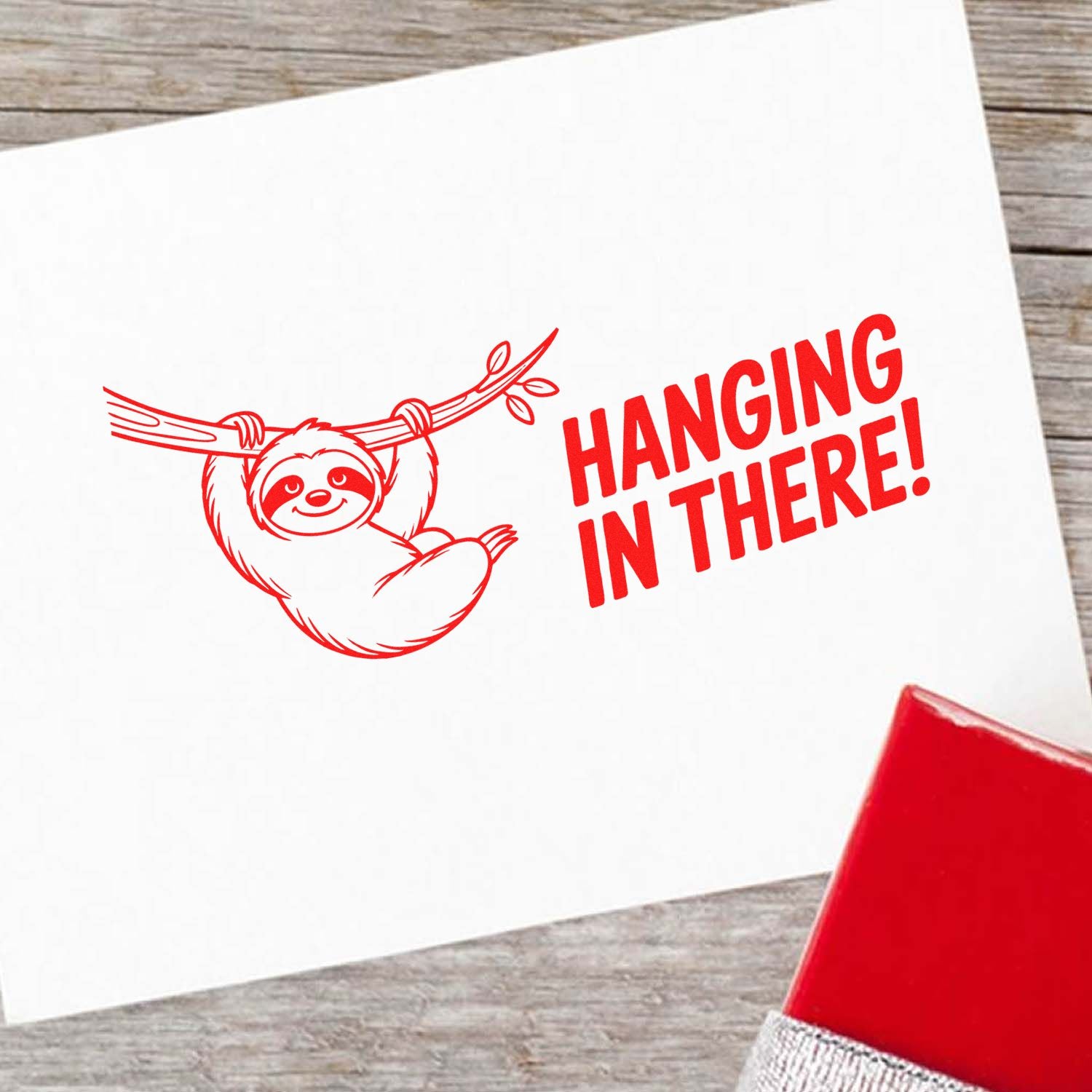 Red sloth hanging in there stamp and seal design on white card, with bold red text and a red seal.