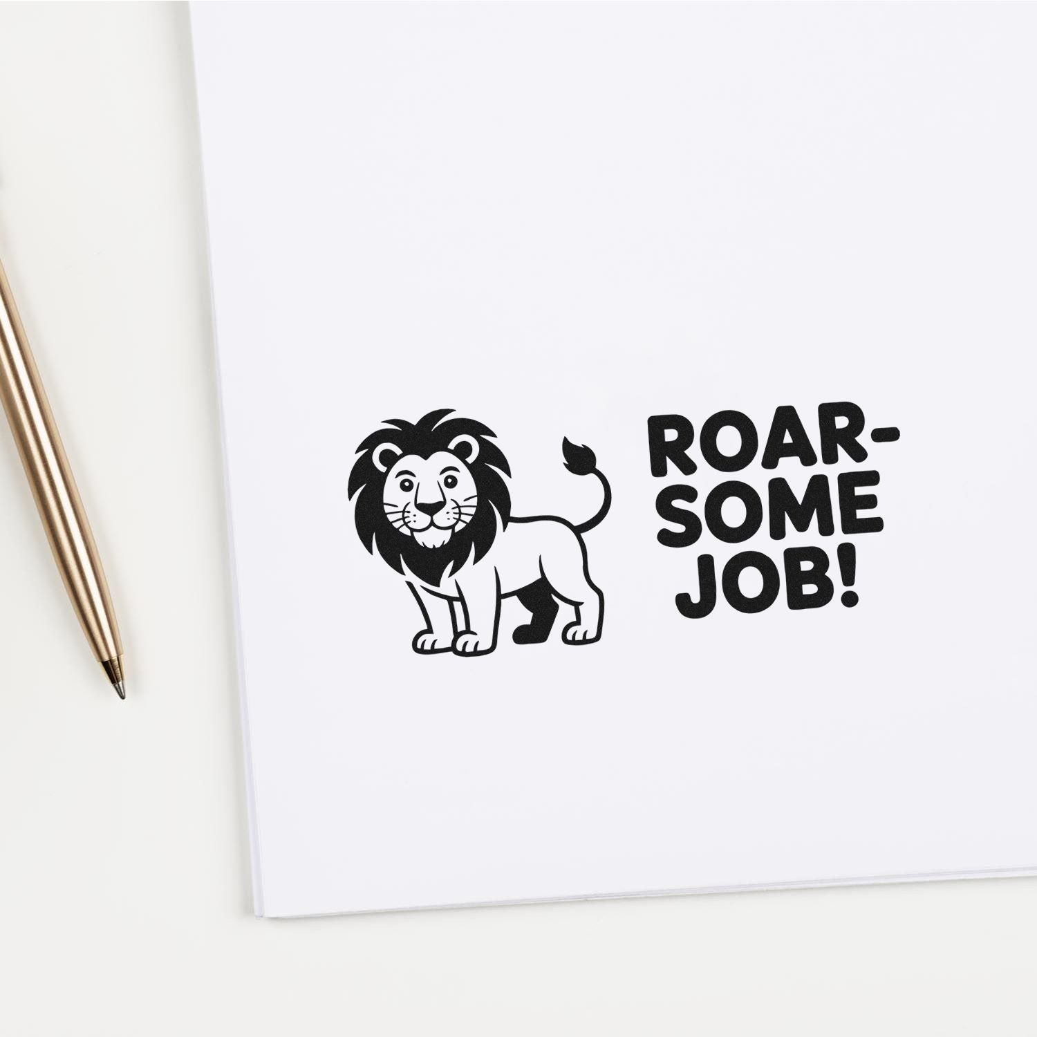 Black lion stamp and seal with ROAR-SOME JOB! on white paper beside a gold pen.