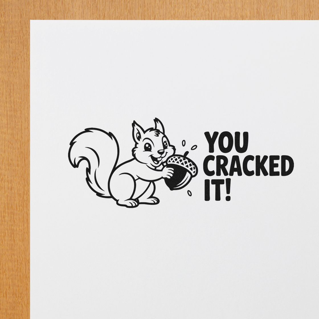 Black squirrel rubber stamp seal with acorn and bold YOU CRACKED IT! text on white paper.