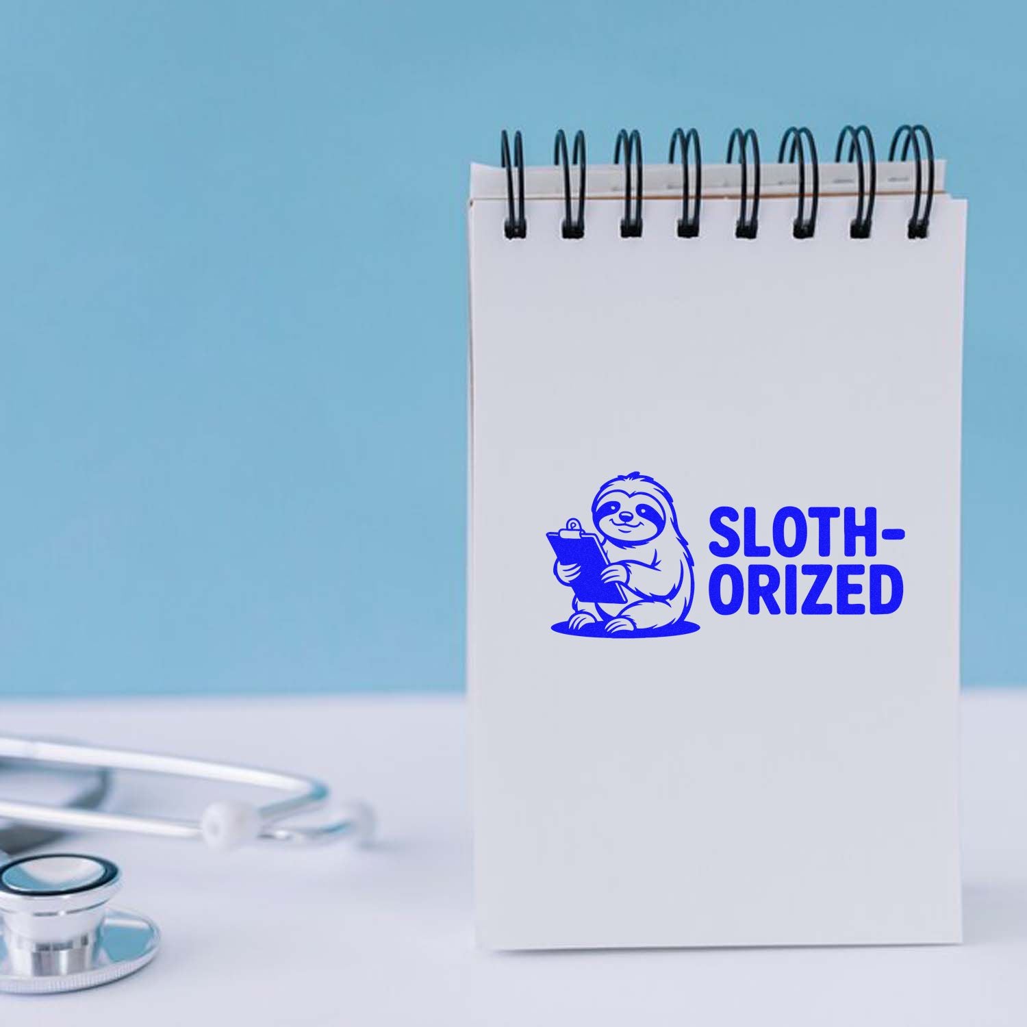 Blue custom stamp on spiral notepad, featuring a sloth holding a clipboard and SLOTH-ORIZED text.