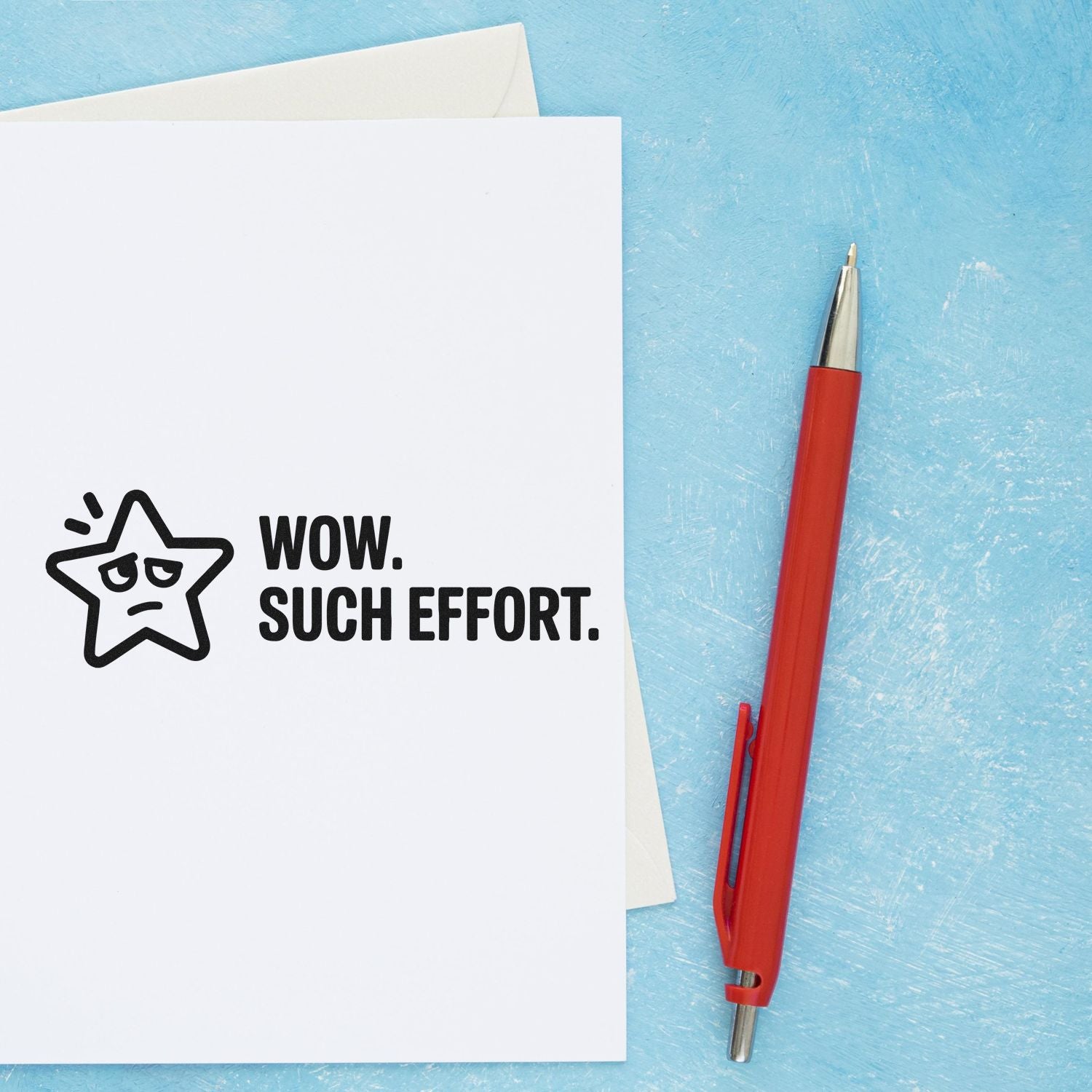 White card with black self-inking stamp reading WOW. SUCH EFFORT. beside a red pen on a blue background.