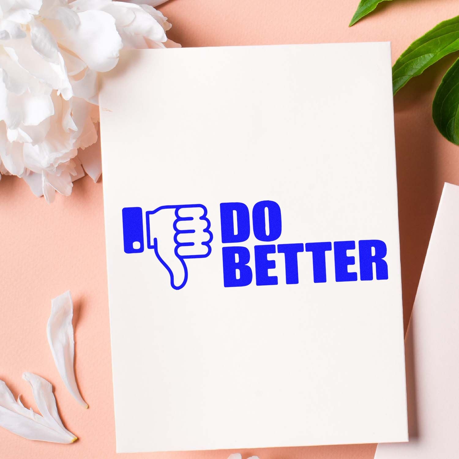 Blue thumbs-down stamp and seal reading DO BETTER on a white card, with peach background, white flowers, and green leaves.
