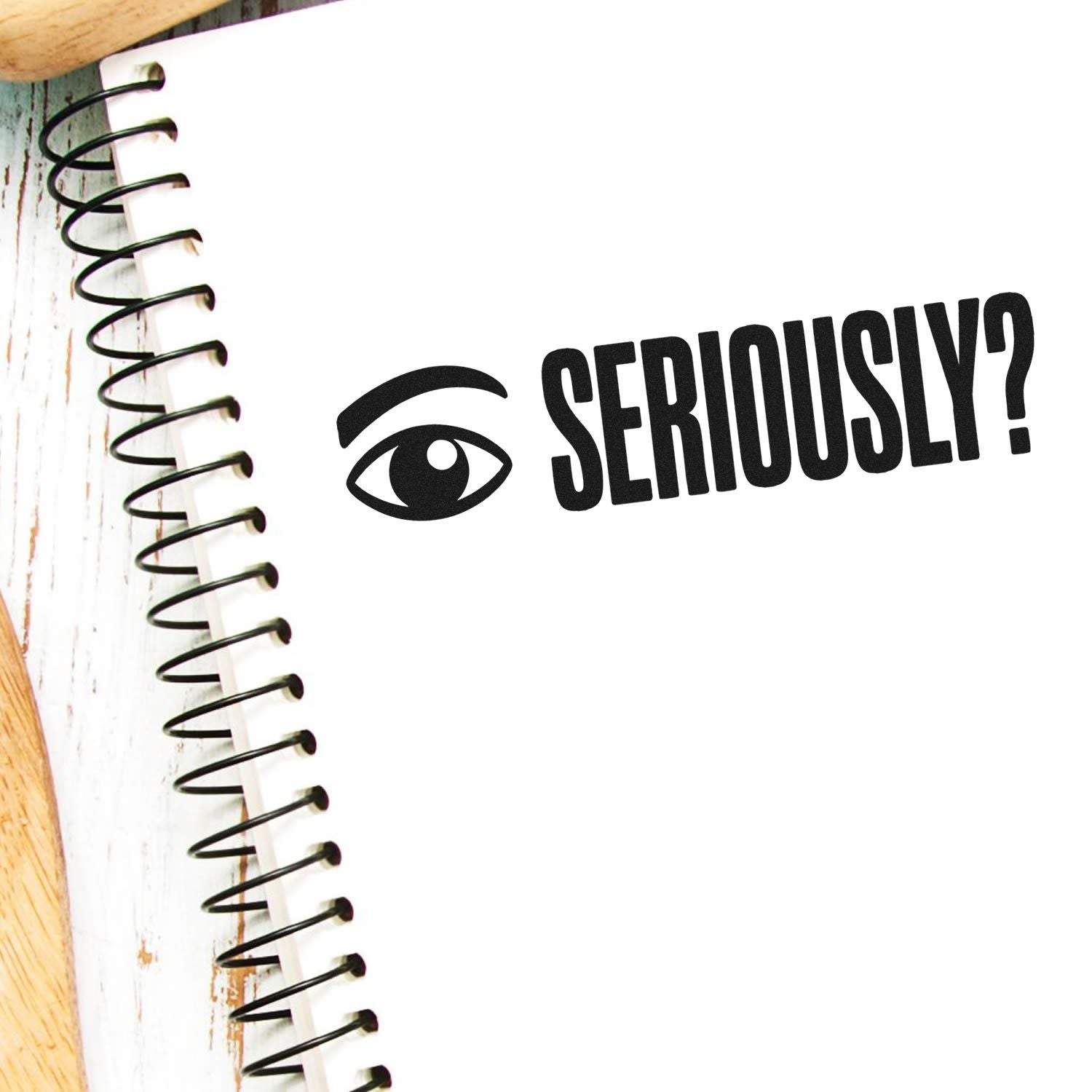 Black stamp-style eye icon and SERIOUSLY? text on a white spiral notebook page, with bold black seal-like design.