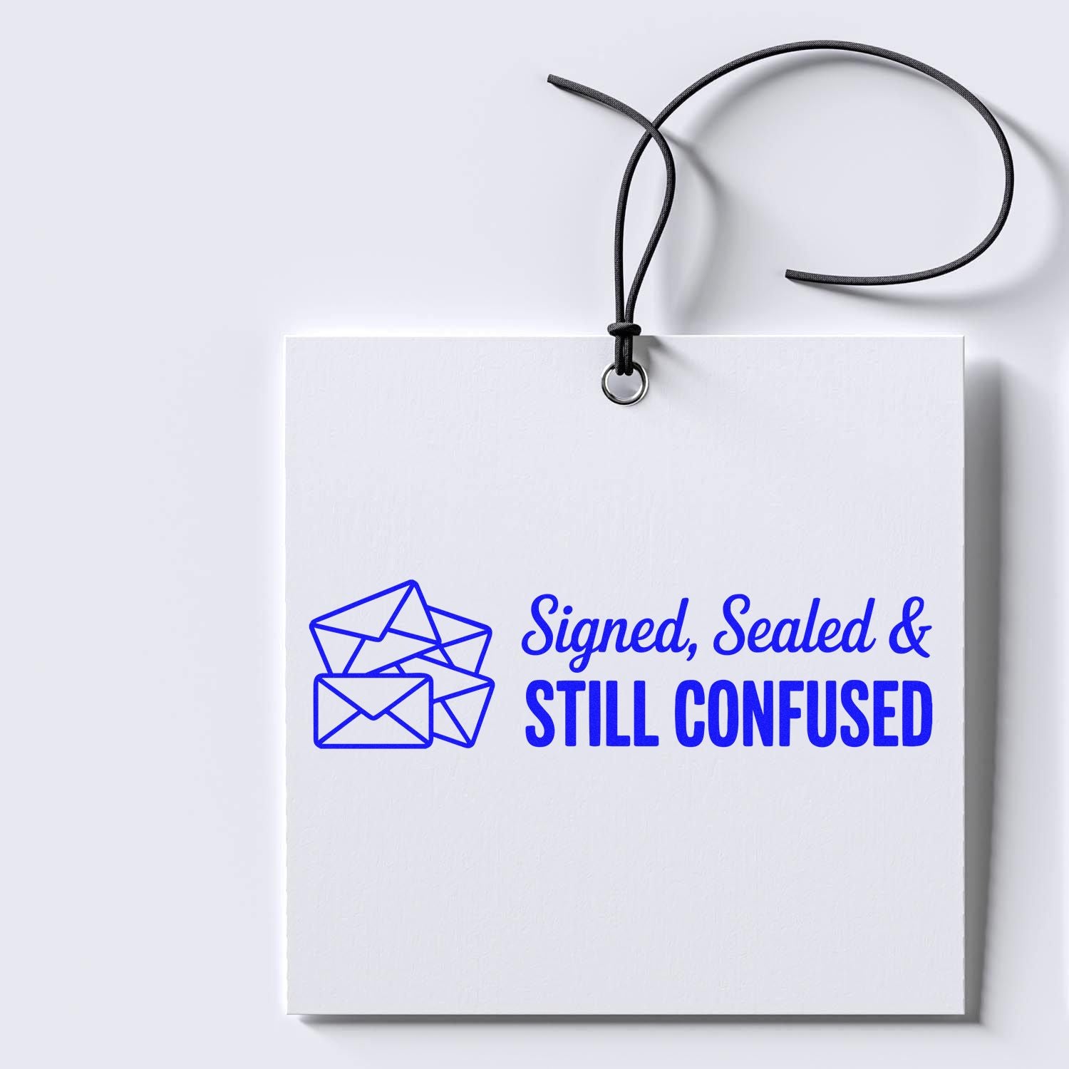 White hanging stamp-and-seal tag with black cord and blue envelope graphic reading Signed, Sealed & STILL CONFUSED