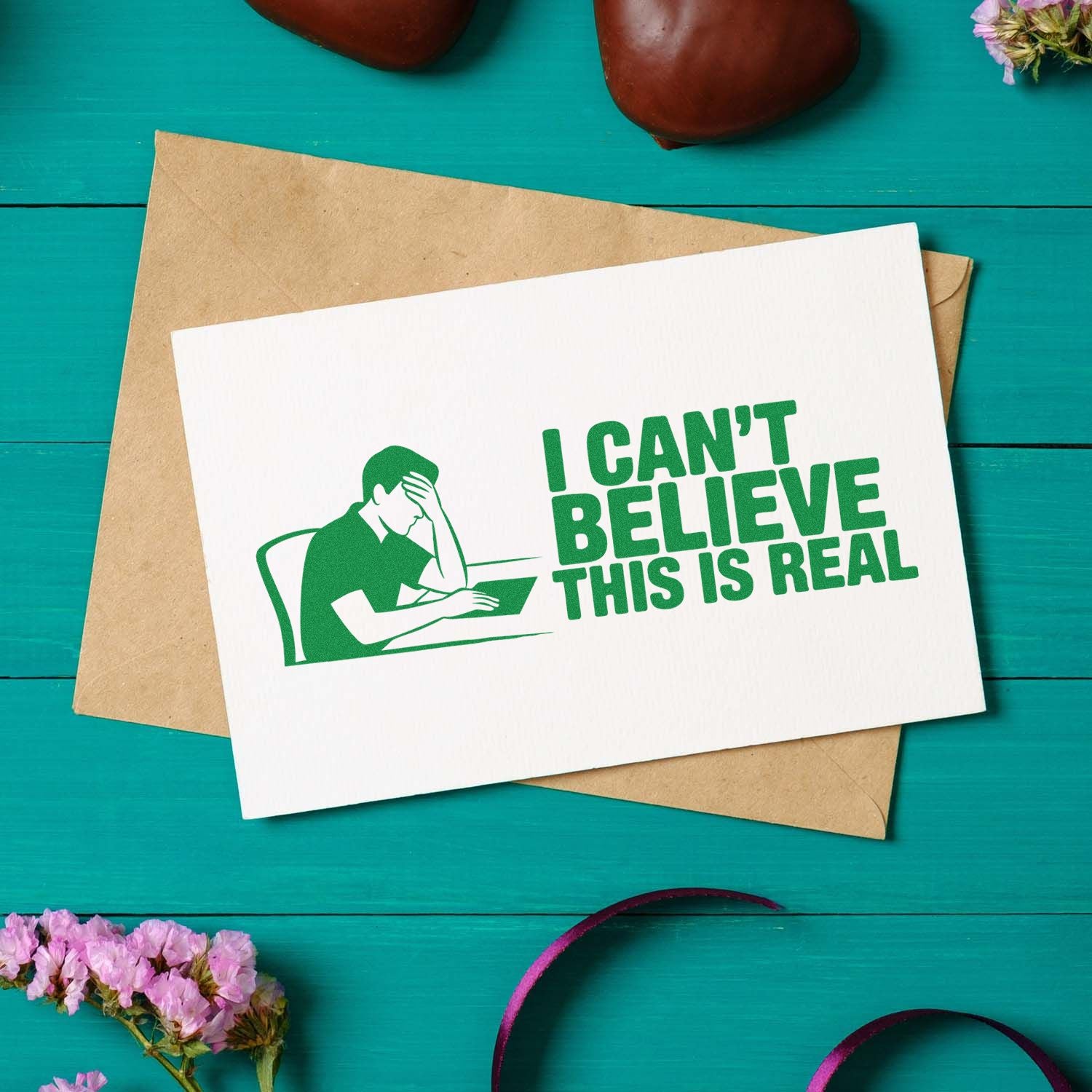 Green stamp/seal design with facepalm figure and I cant believe this is real on a white card over a kraft envelope.