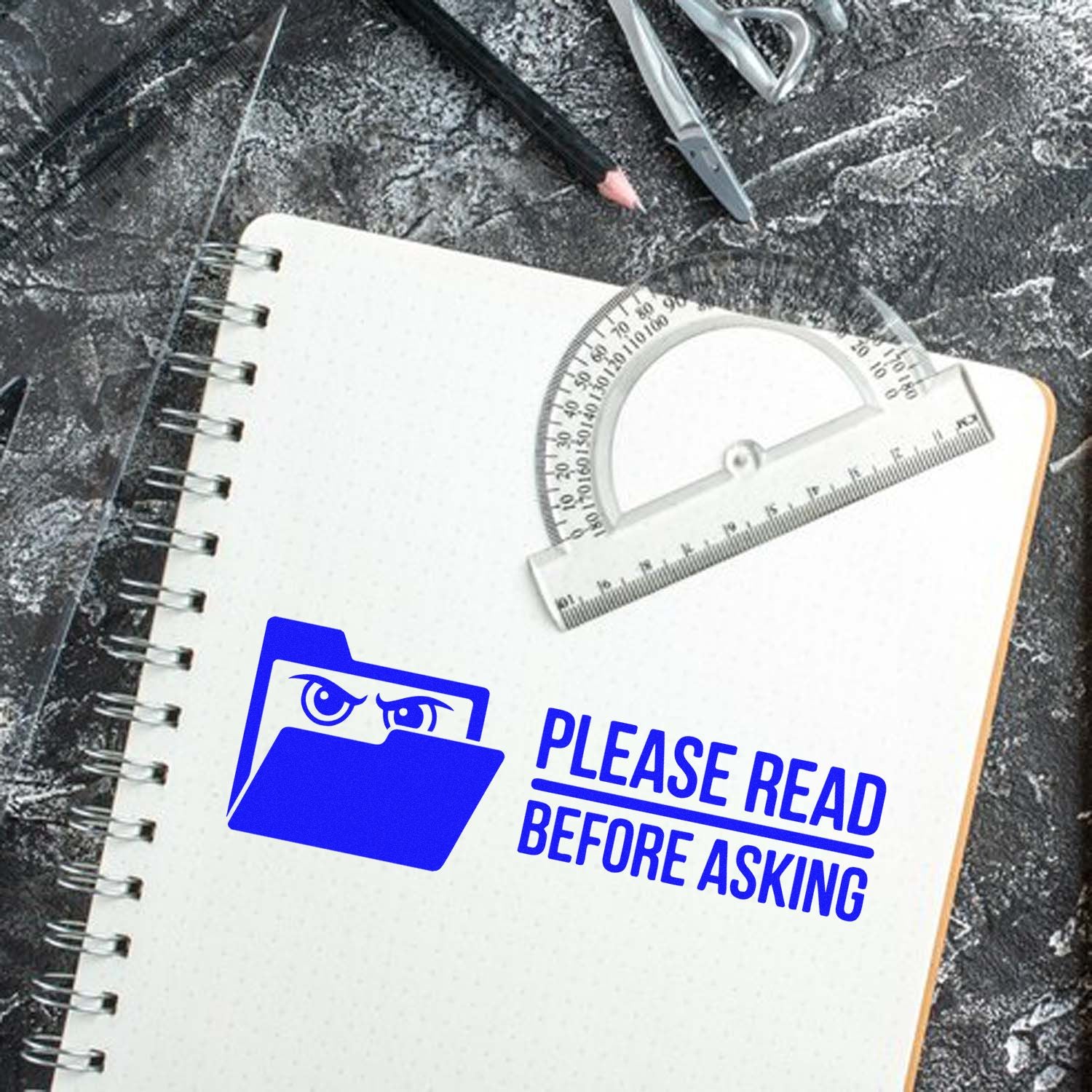 Blue custom stamp and seal reading Please read before asking on a white spiral notebook with drafting tools.