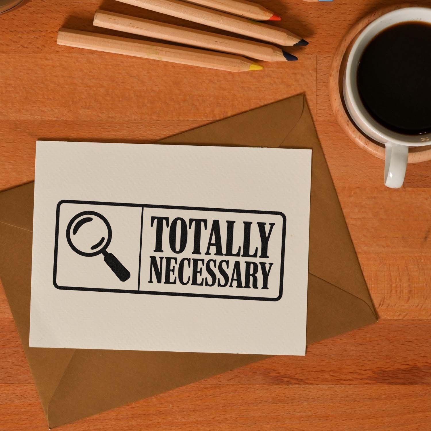 Black Totally Necessary stamp and seal on white card over brown envelope, with coffee and colored pencils.