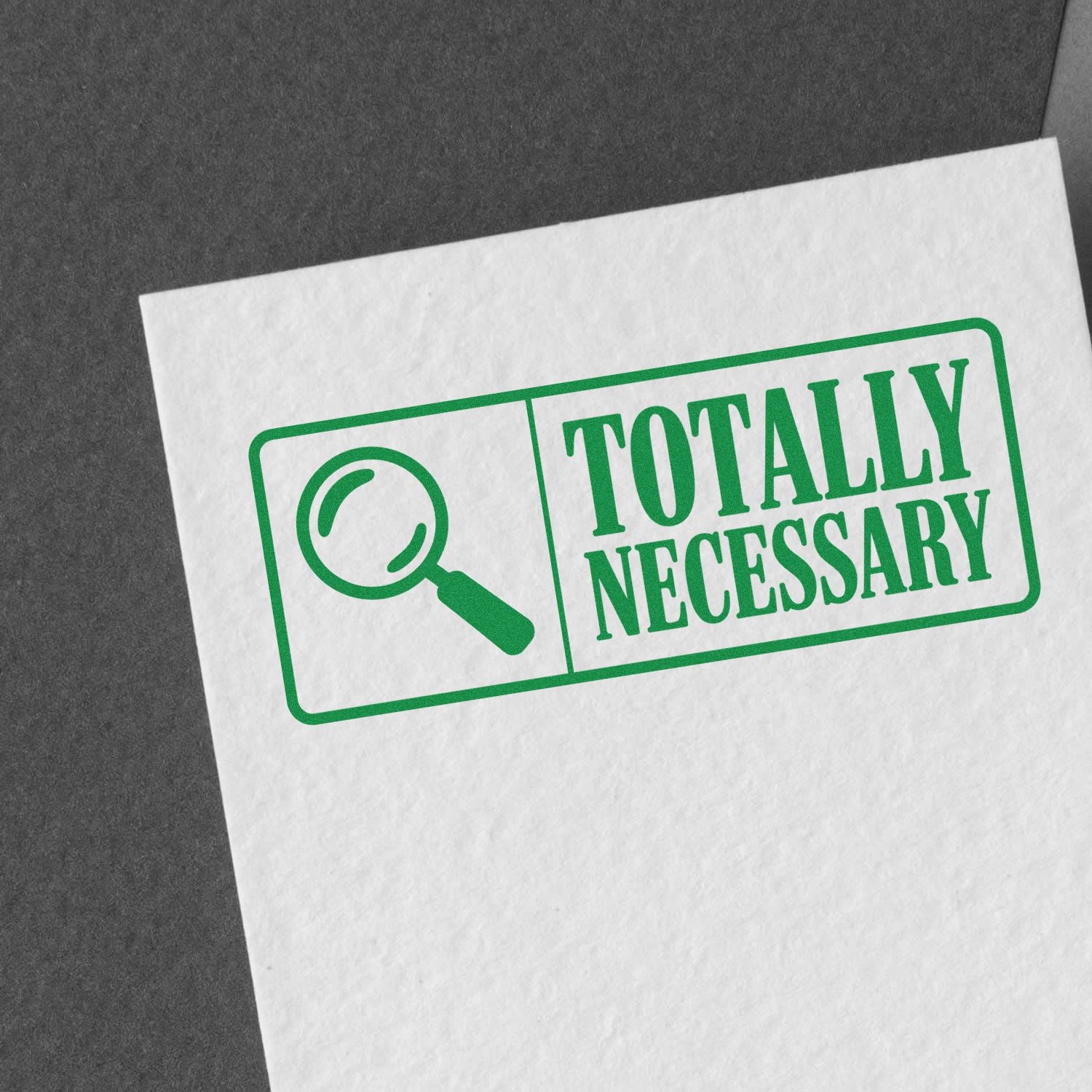 Green rubber stamp seal with magnifying glass icon and Totally Necessary text on white paper.