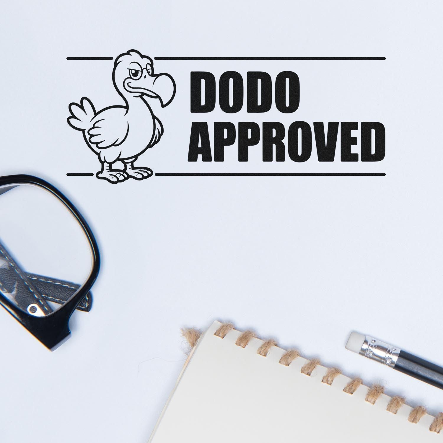 Black DODO APPROVED rubber stamp seal with cartoon dodo on white background, beside stationery.