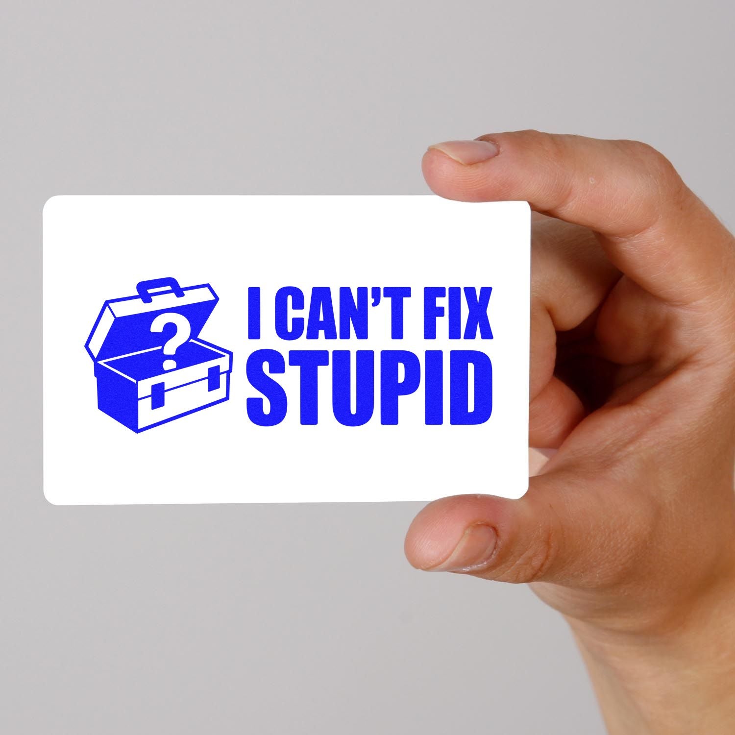 Blue custom stamp and seal card with toolbox icon and I CANT FIX STUPID, held in a hand on white background.