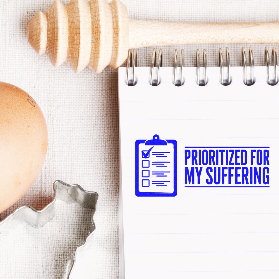 Blue stamp and seal imprint on a spiral notebook reads PRIORITIZED FOR MY SUFFERING with a clipboard icon.