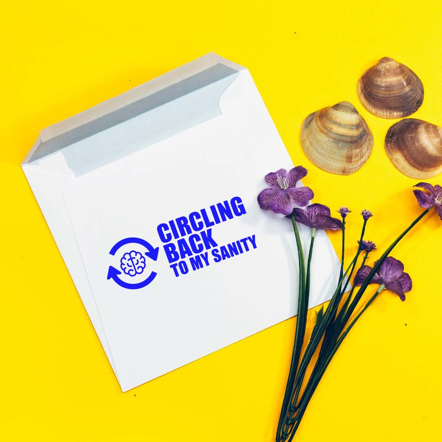White mailer envelope with blue stamp reading Circling Back to My Sanity, on bright yellow with purple flowers and seashells.