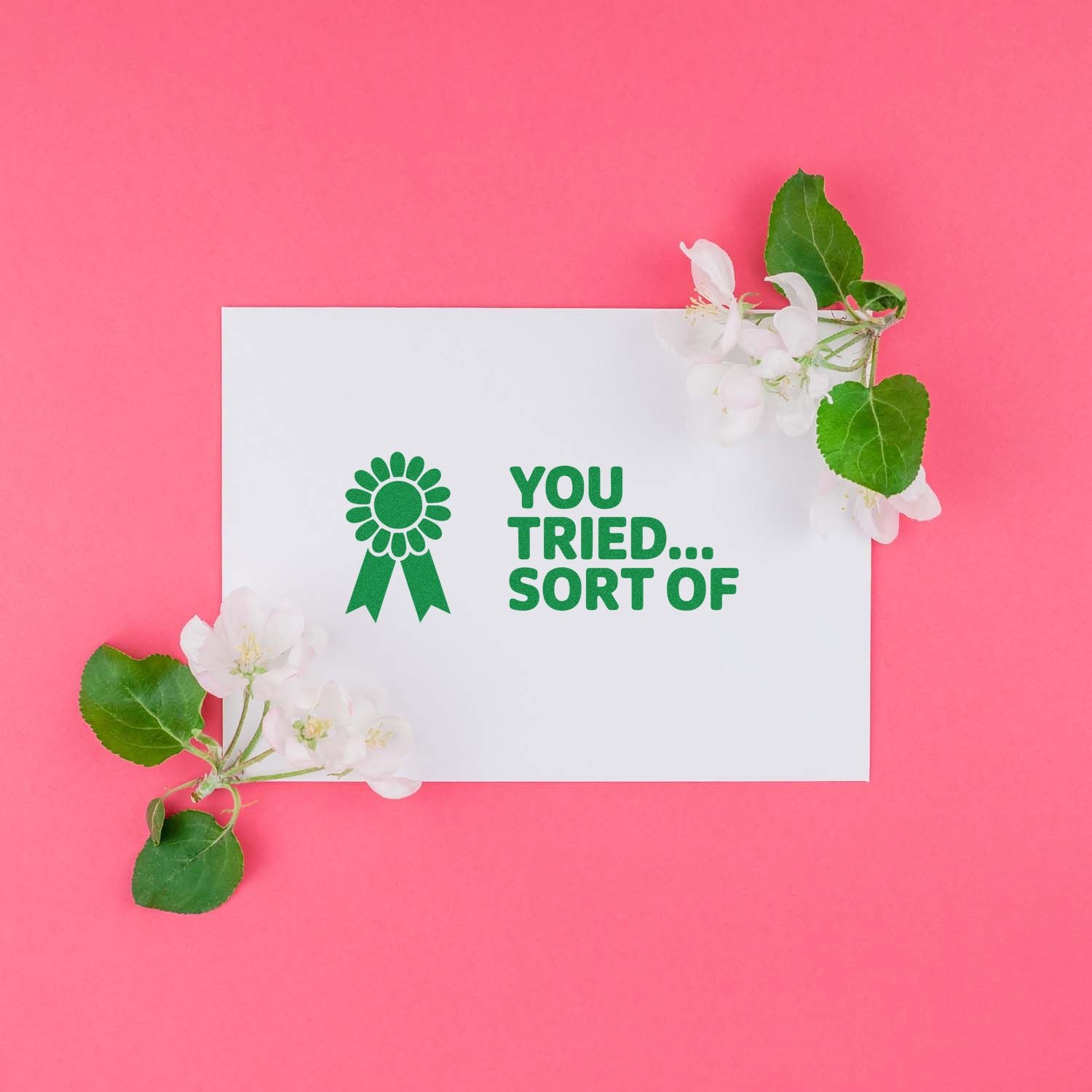 White stamp seal card with green YOU TRIED... SORT OF text on pink background, framed by white blossoms and green leaves.