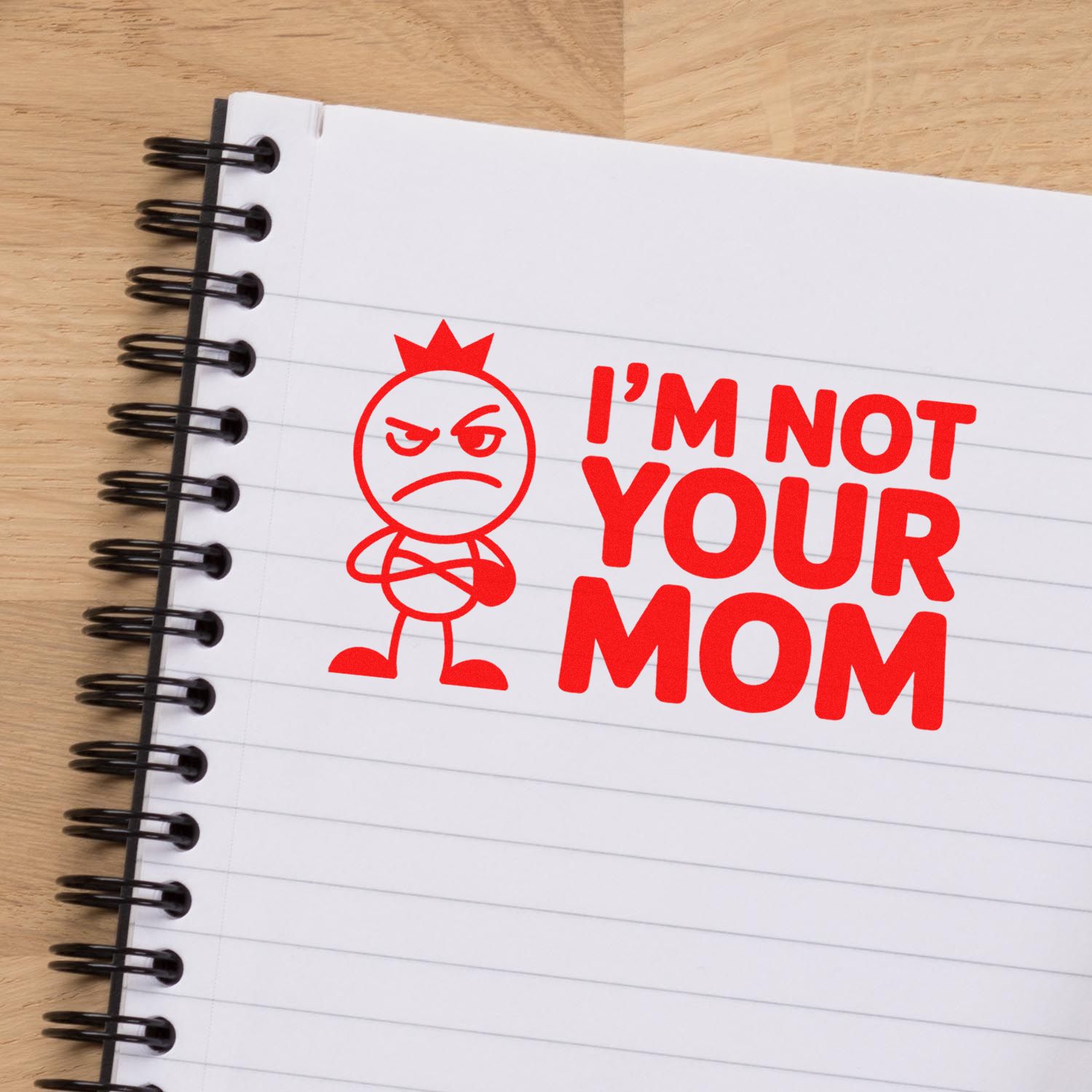 Red self-inking stamp and seal reading IM NOT YOUR MOM with angry face on a lined spiral notebook
