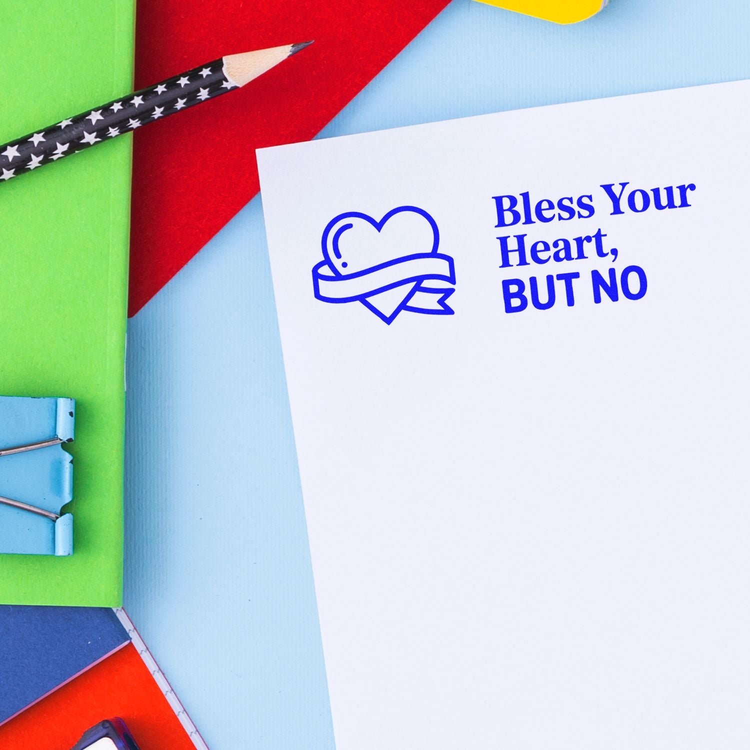 White card with blue heart ribbon stamp and Bless Your Heart, BUT NO text, surrounded by colorful stamp and seal supplies.