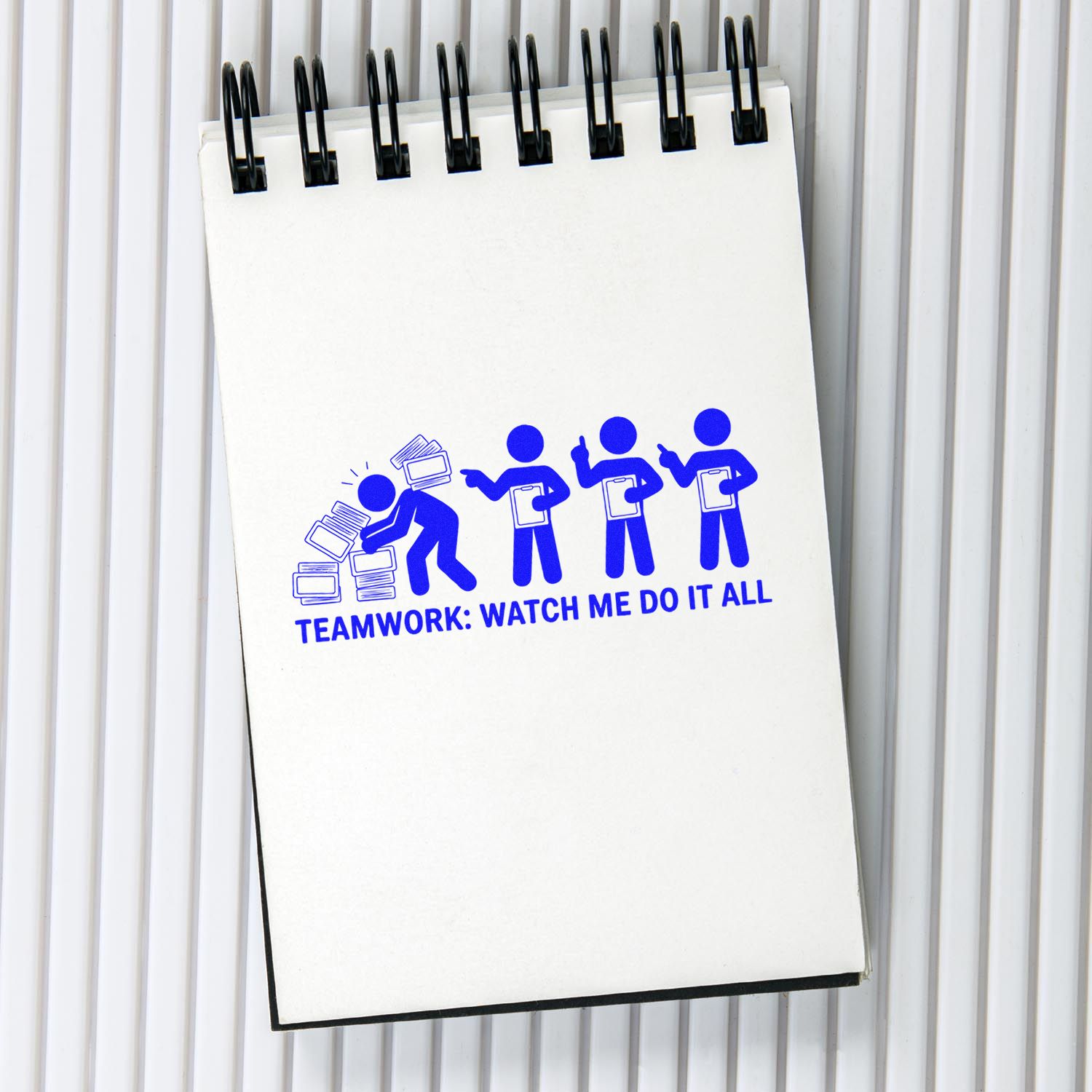 White spiral notepad with blue teamwork stamp graphic, black binding, and seal-style office stamp design.