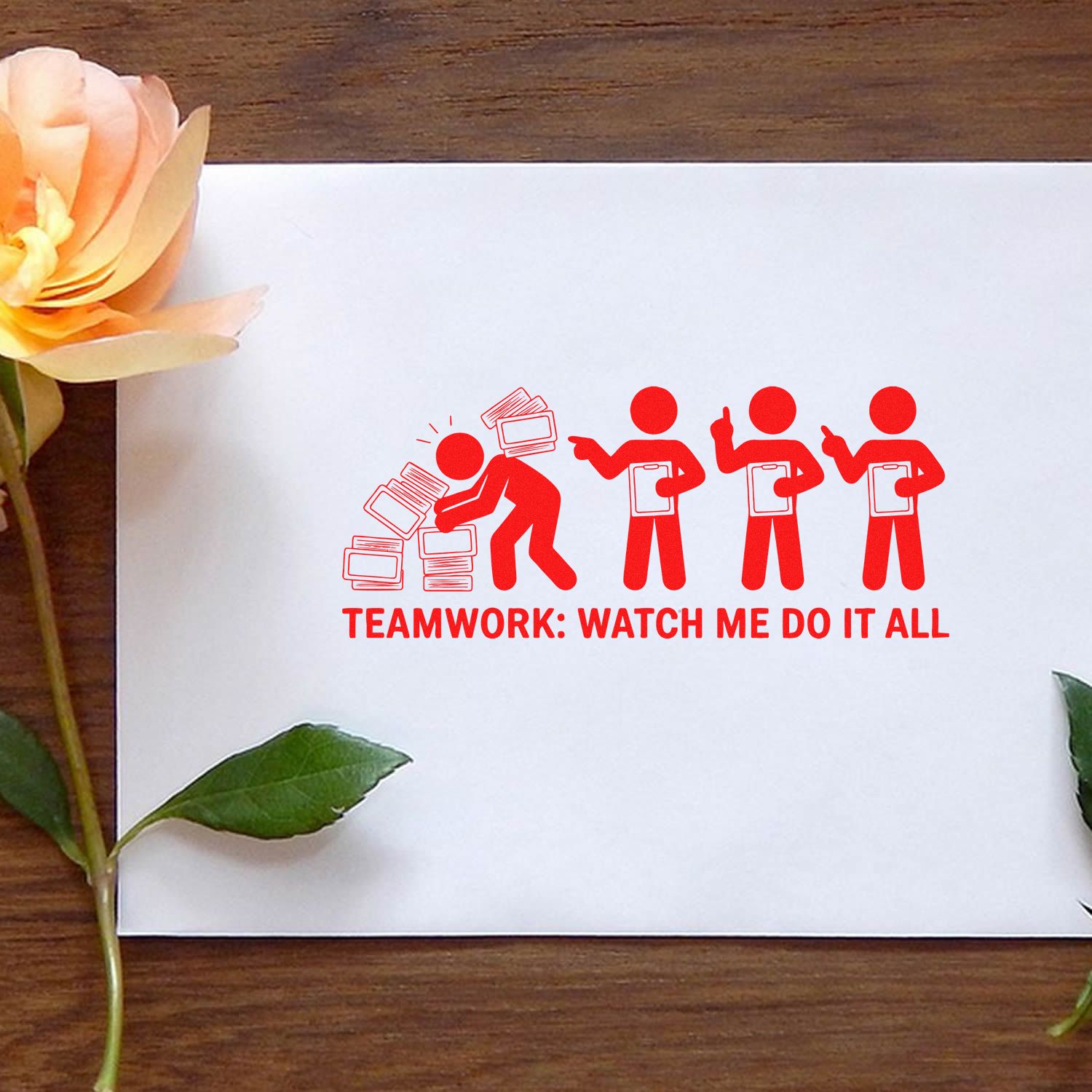 Red teamwork self-inking stamp/seal on white paper, with stick figures and text on a wood table, peach flower accents.