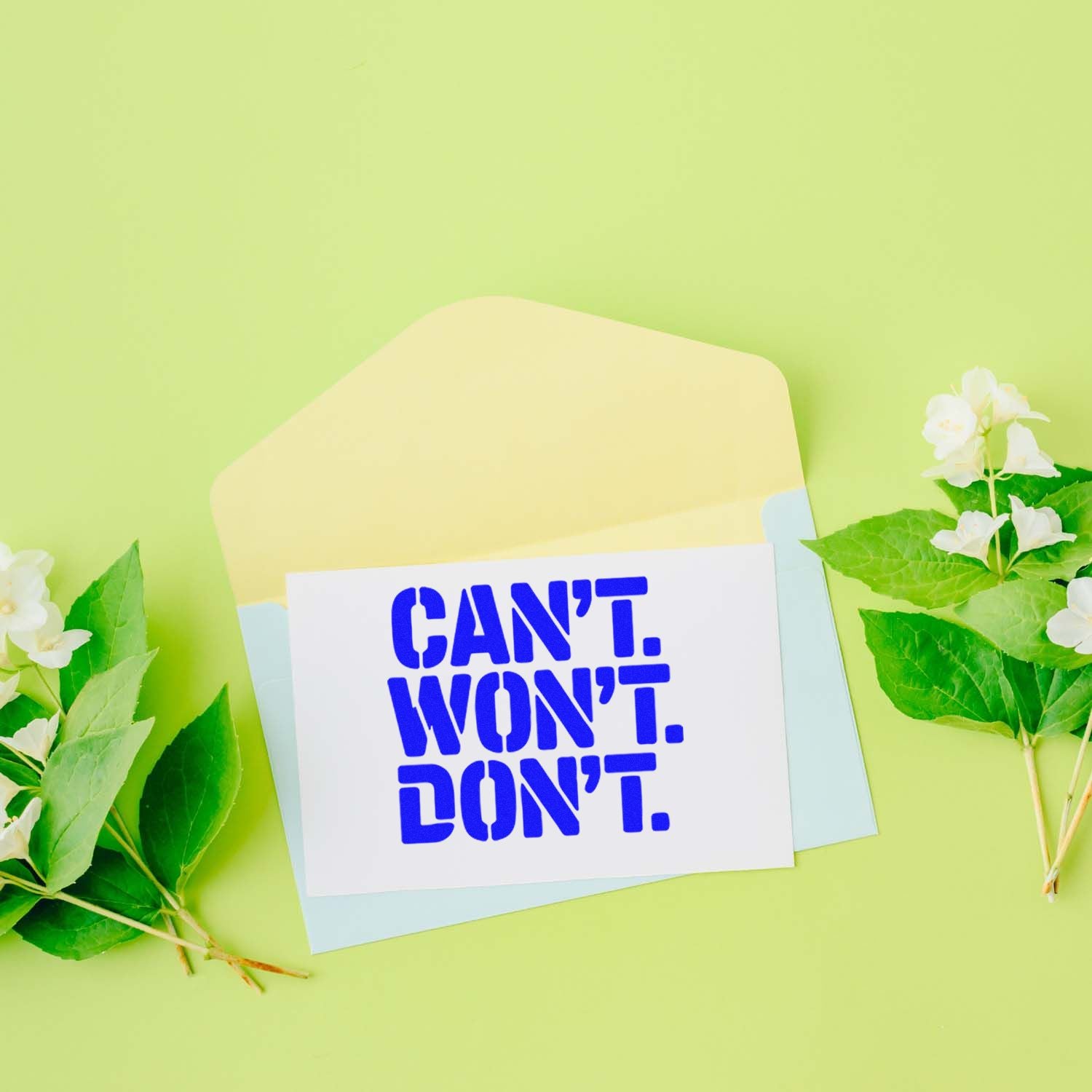 Blue seal stamp reading CANT. WONT. DONT. on white card, with pastel envelope and green floral accents.