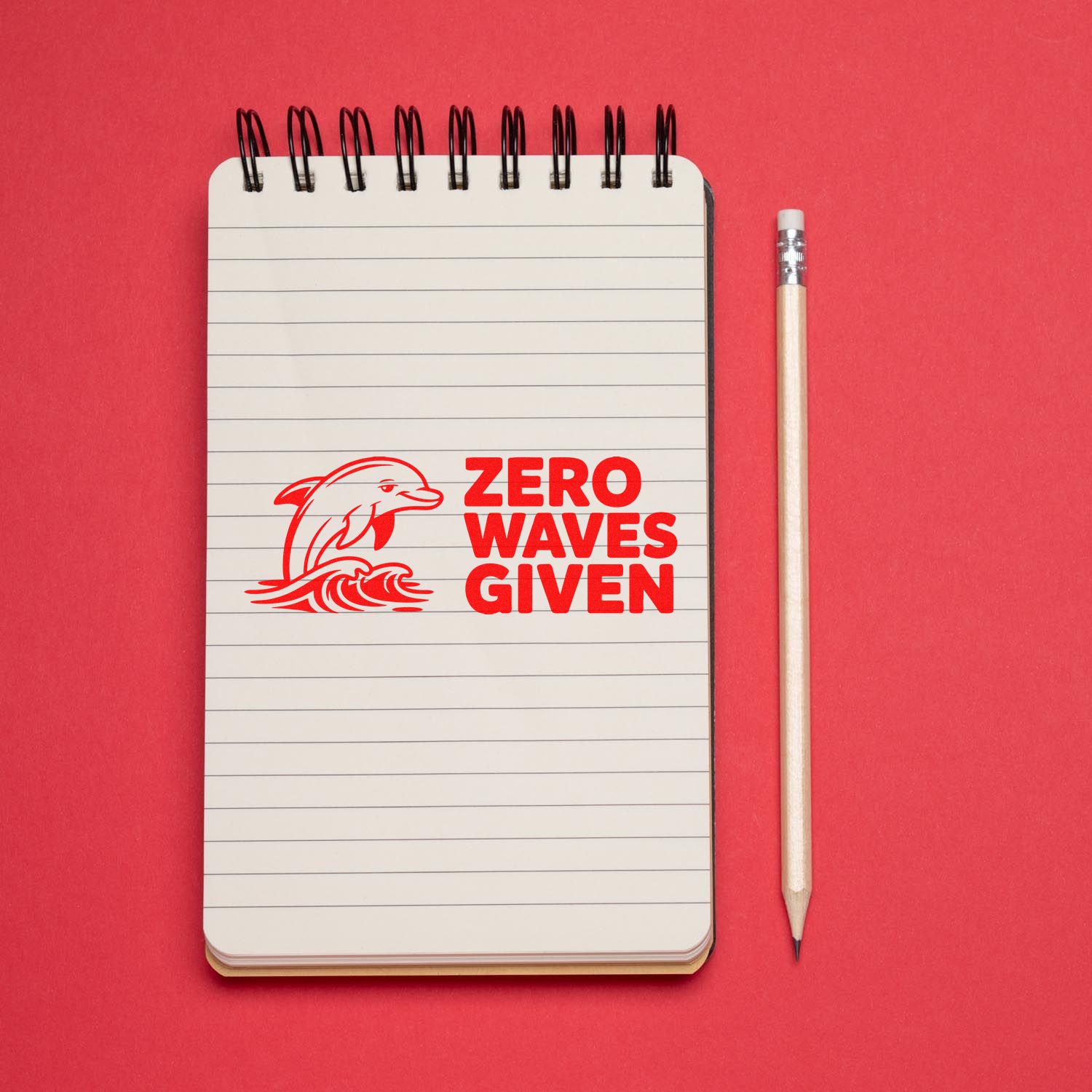 Red stamp reading ZERO WAVES GIVEN with dolphin and wave on lined notebook, beside a pencil on a red background.