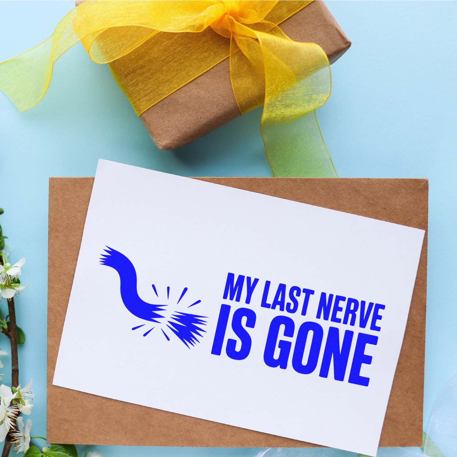 Blue custom stamp and seal design reading My Last Nerve Is Gone on white card, over a kraft envelope with yellow ribbon gift box.