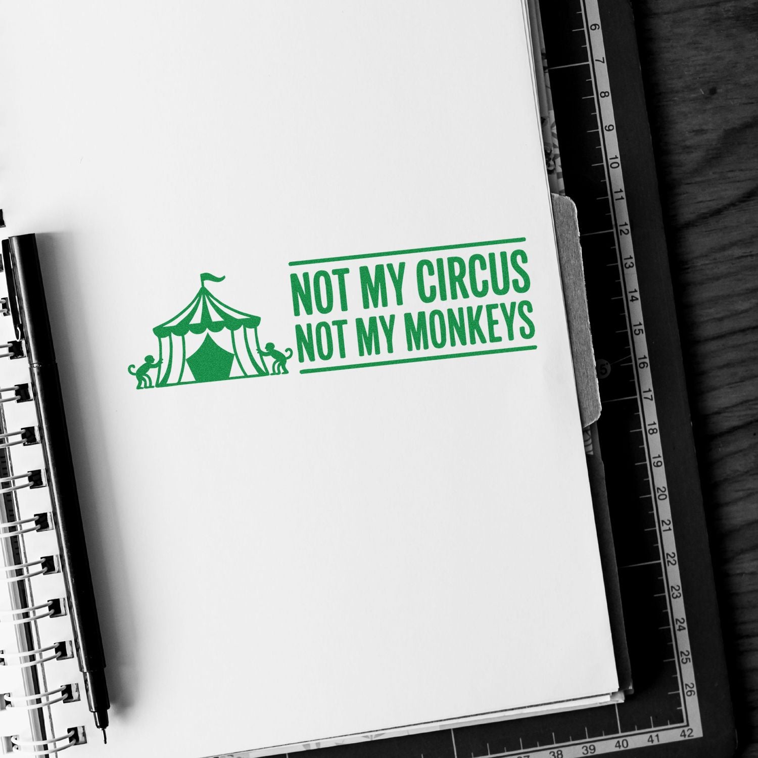 Green stamp and seal reading NOT MY CIRCUS NOT MY MONKEYS with circus tent and monkeys on a white notebook page.