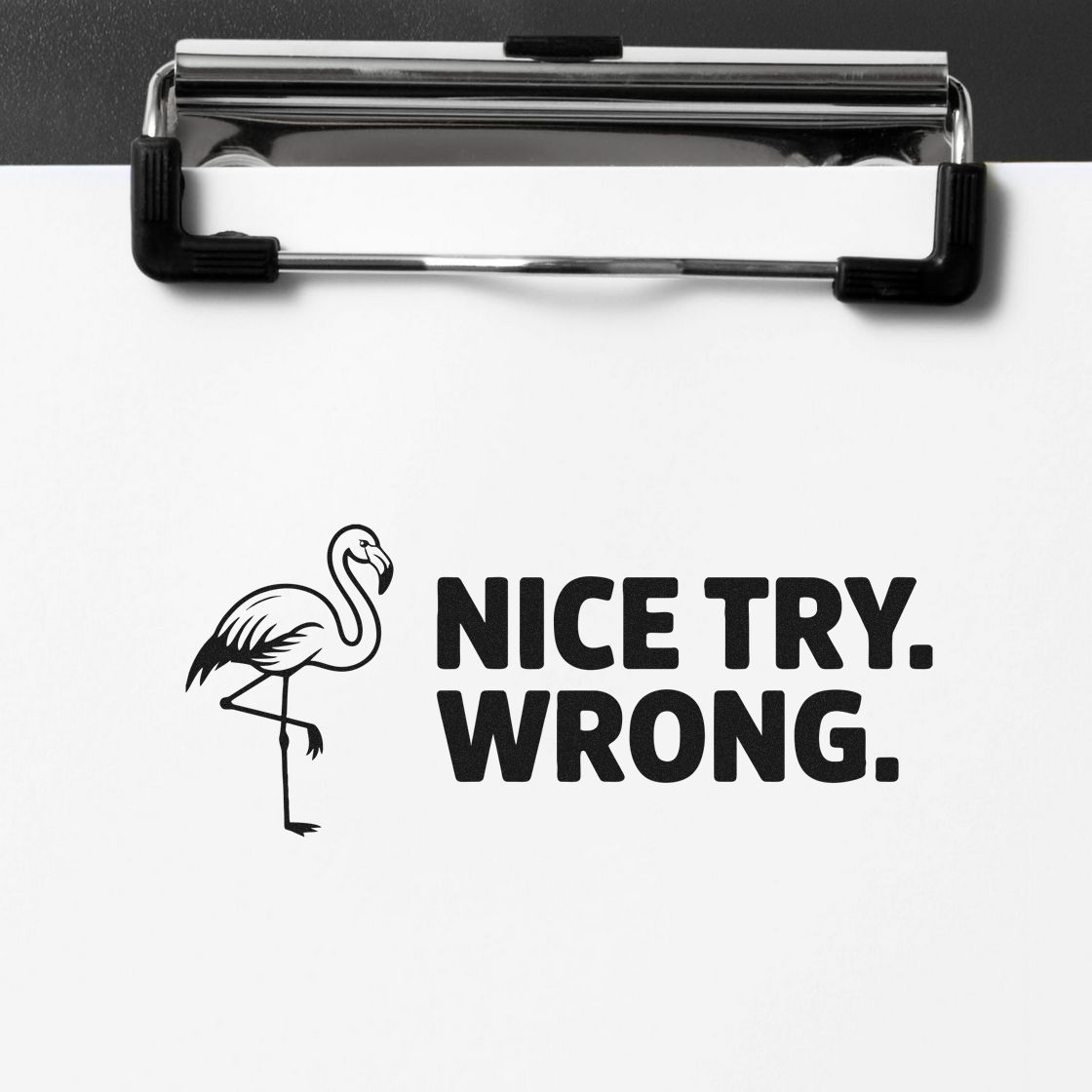 Black flamingo stamp seal with bold NICE TRY. WRONG. on white paper, clipped to a chrome clipboard.