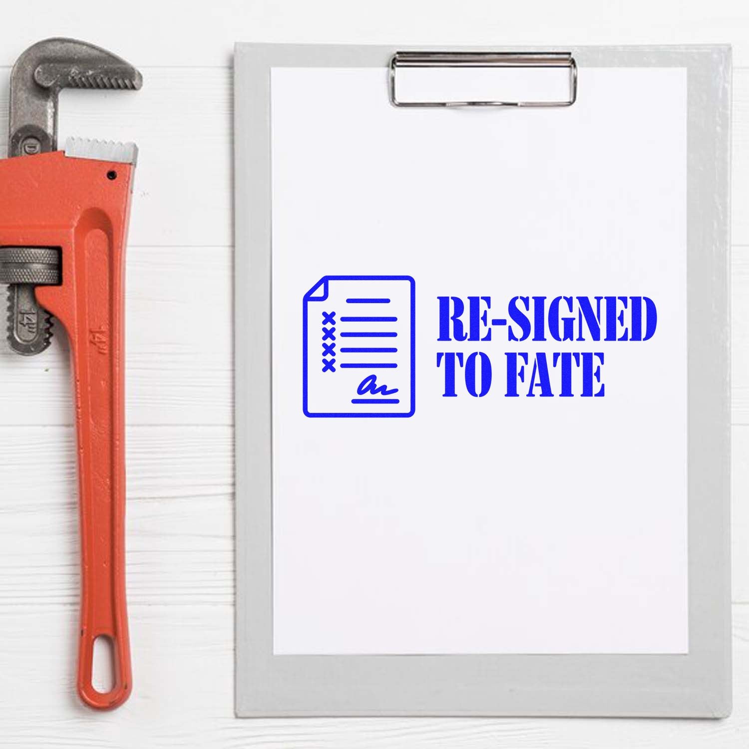 Orange pipe wrench beside clipboard with blue self-inking stamp seal reading RE-SIGNED TO FATE