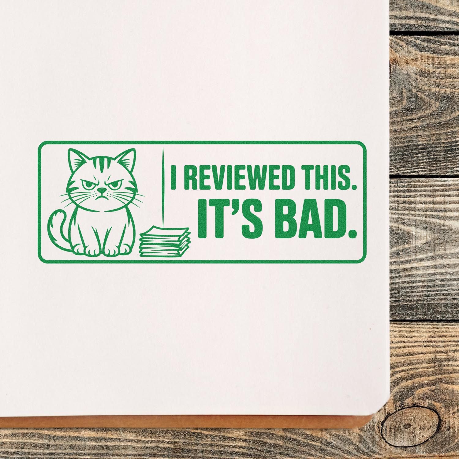 Green rubber stamp seal with grumpy cat and papers, reading I REVIEWED THIS. ITS BAD. on white paper.