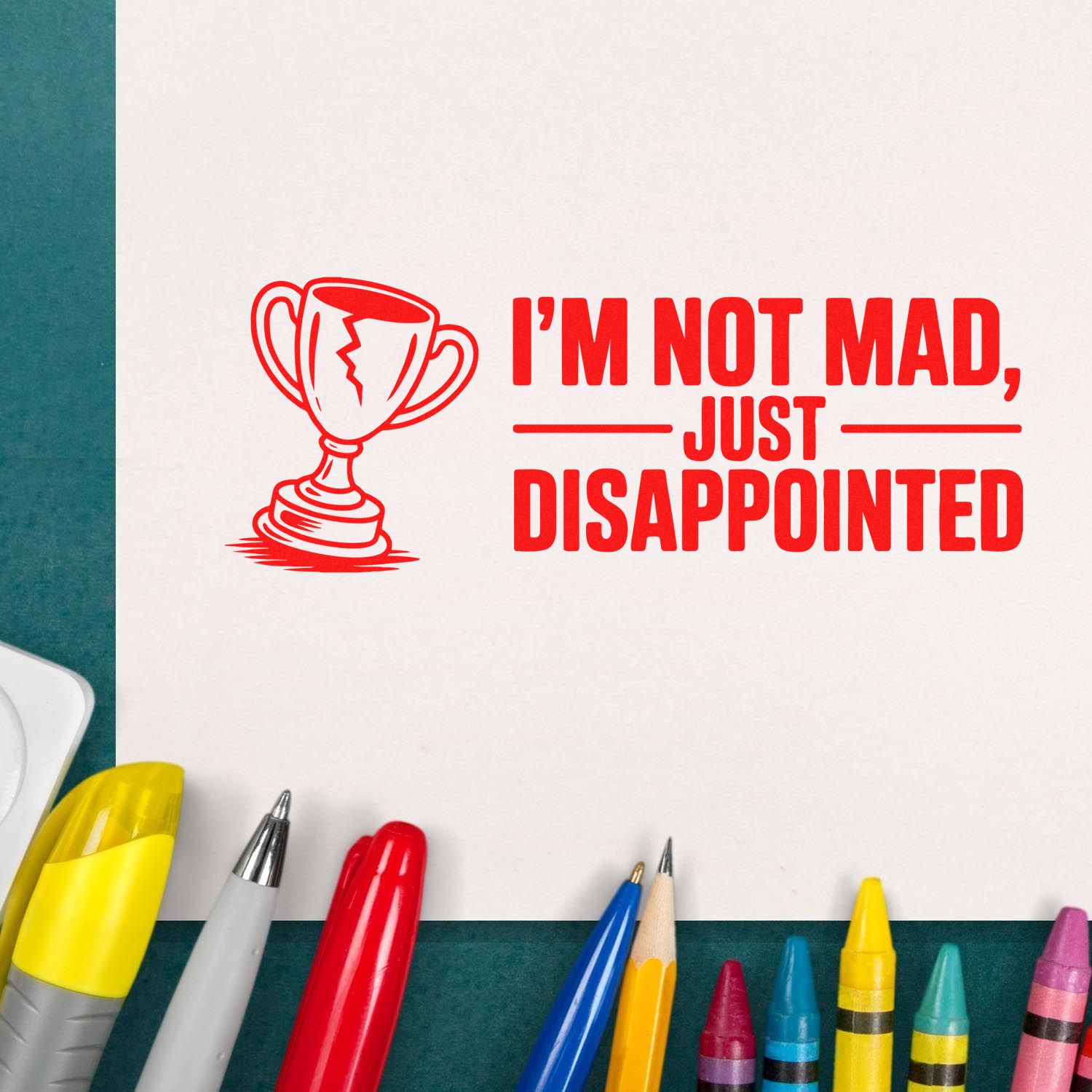Red stamp seal with trophy icon and text Im not mad, just disappointed on white paper, surrounded by colorful pens.