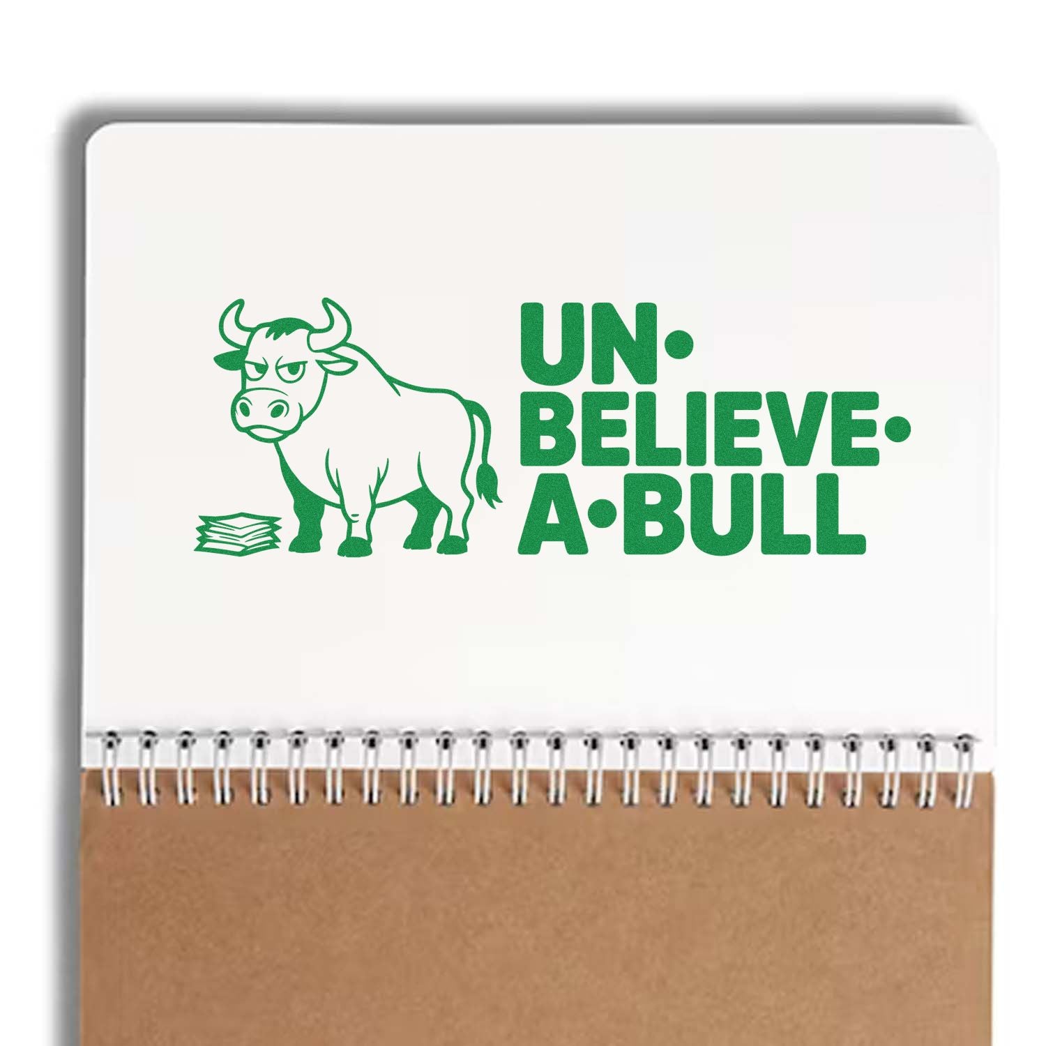 Green bull-themed stamp and seal design with UN-BELIEVE-A-BULL text on a white spiral notebook with kraft cover.