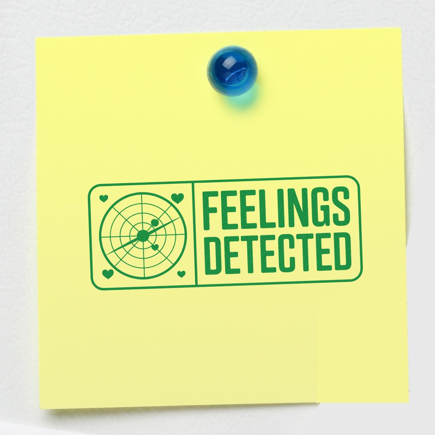 Yellow note with blue pushpin and green rubber stamp seal reading FEELINGS DETECTED.