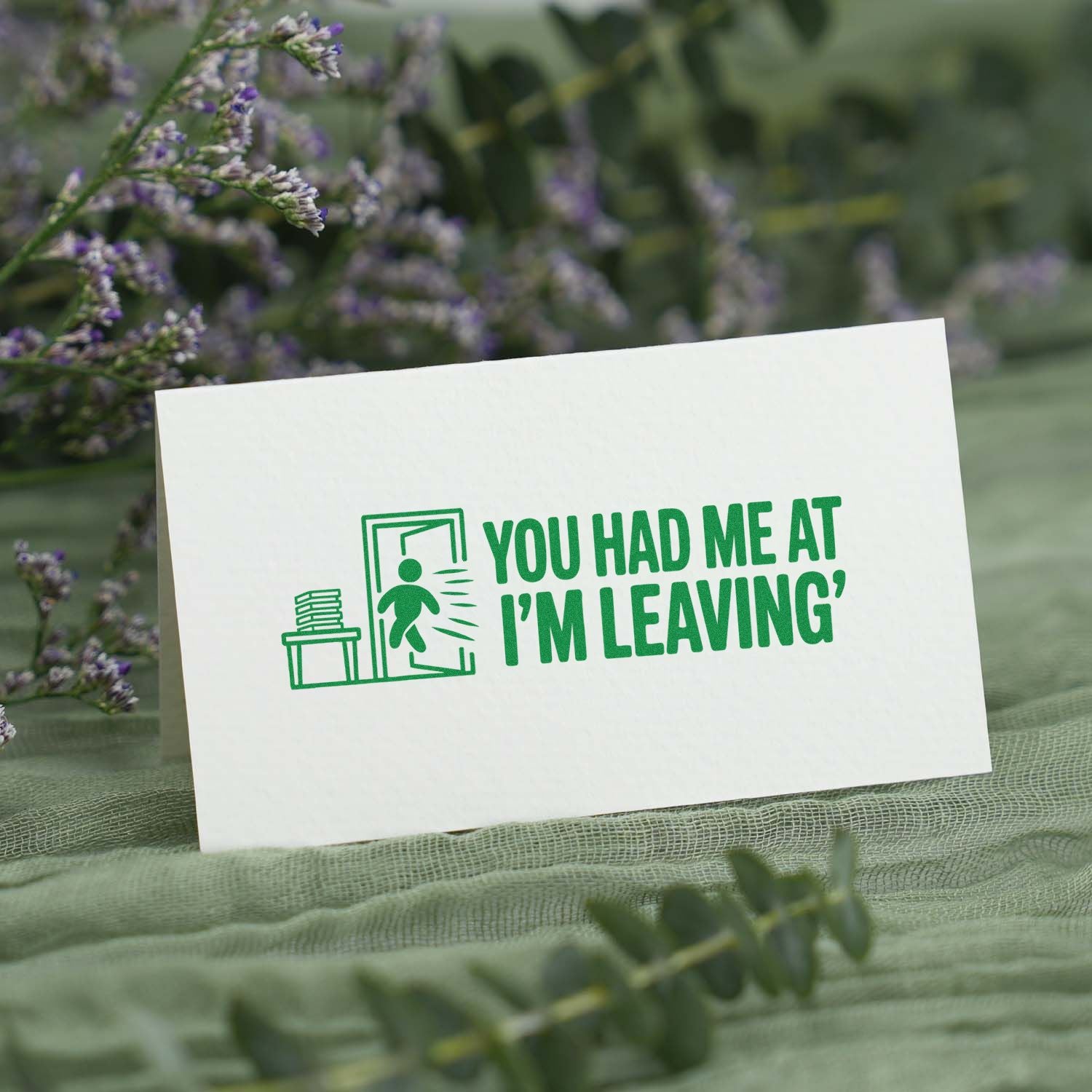 Green custom rubber stamp and seal on white card with door icon and "You had me at I'm leaving" amid purple florals.