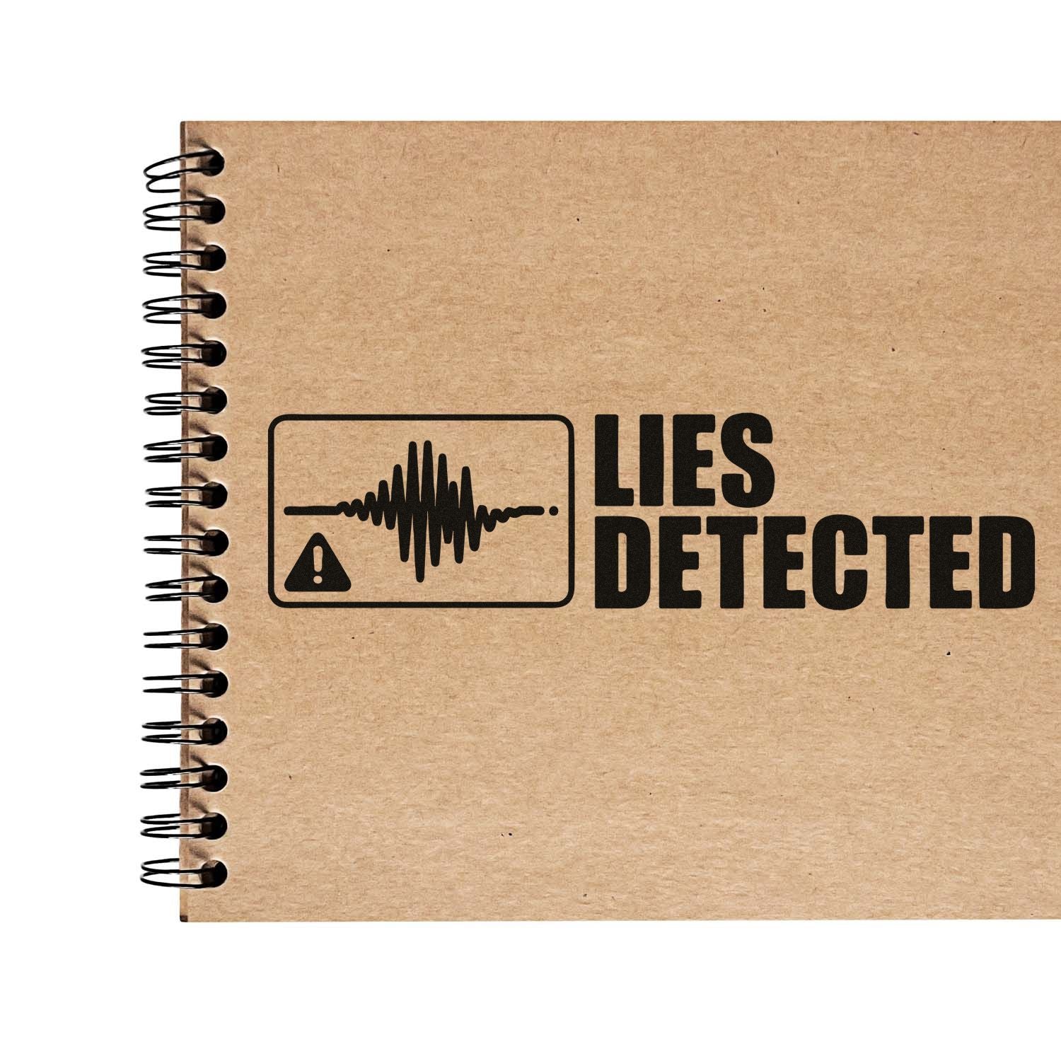 Black LIES DETECTED stamp with waveform and warning icon on kraft brown spiral notebook cover.