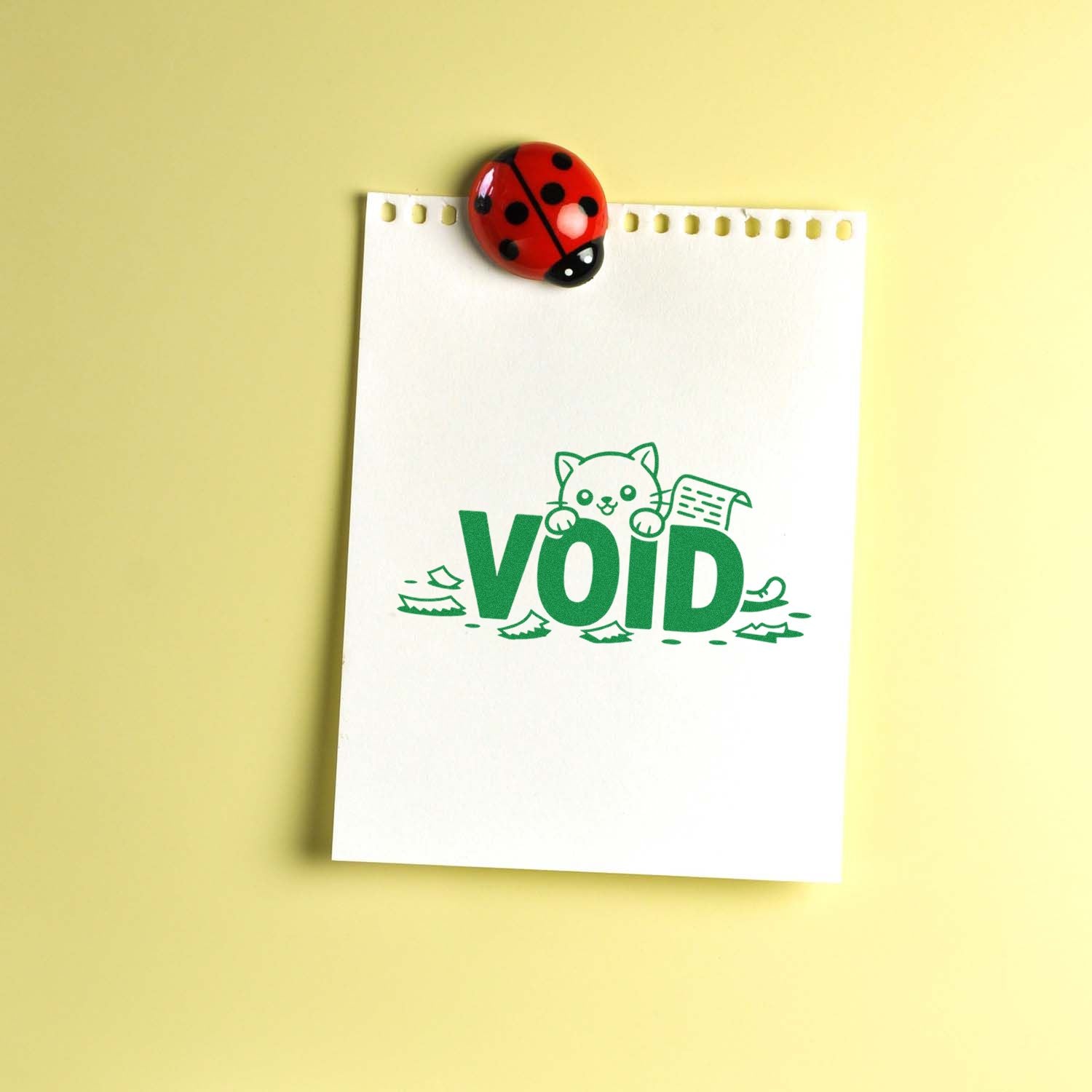 Green VOID stamp and red ladybug seal on white notepad, with pale yellow background.