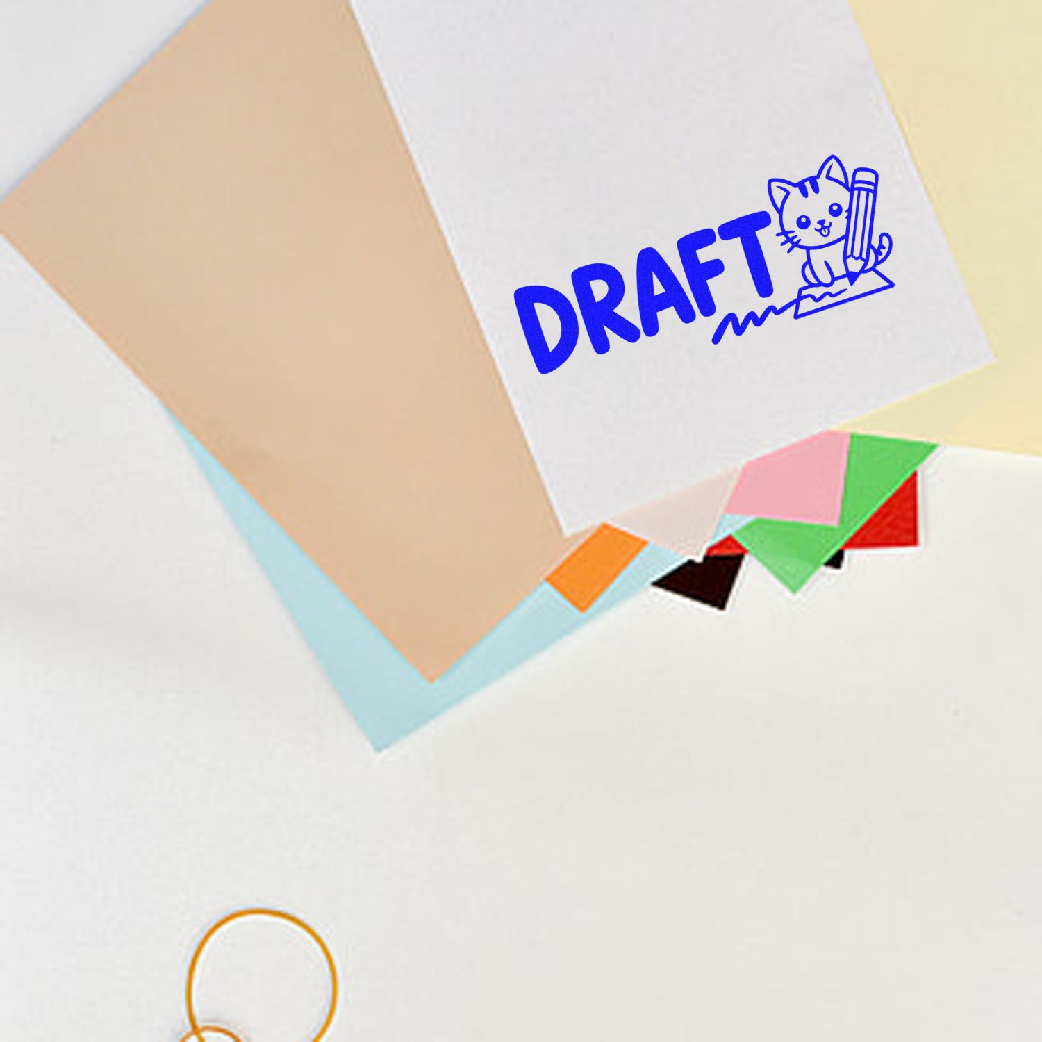 Blue DRAFT stamp seal with cat and pencil on white paper, layered with pastel and colorful paper tabs.
