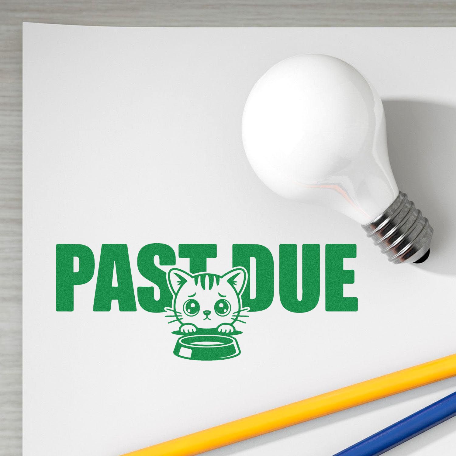 White light bulb stamp seal with green PAST DUE text, cat and bowl icon on white paper, with yellow and blue pencils.