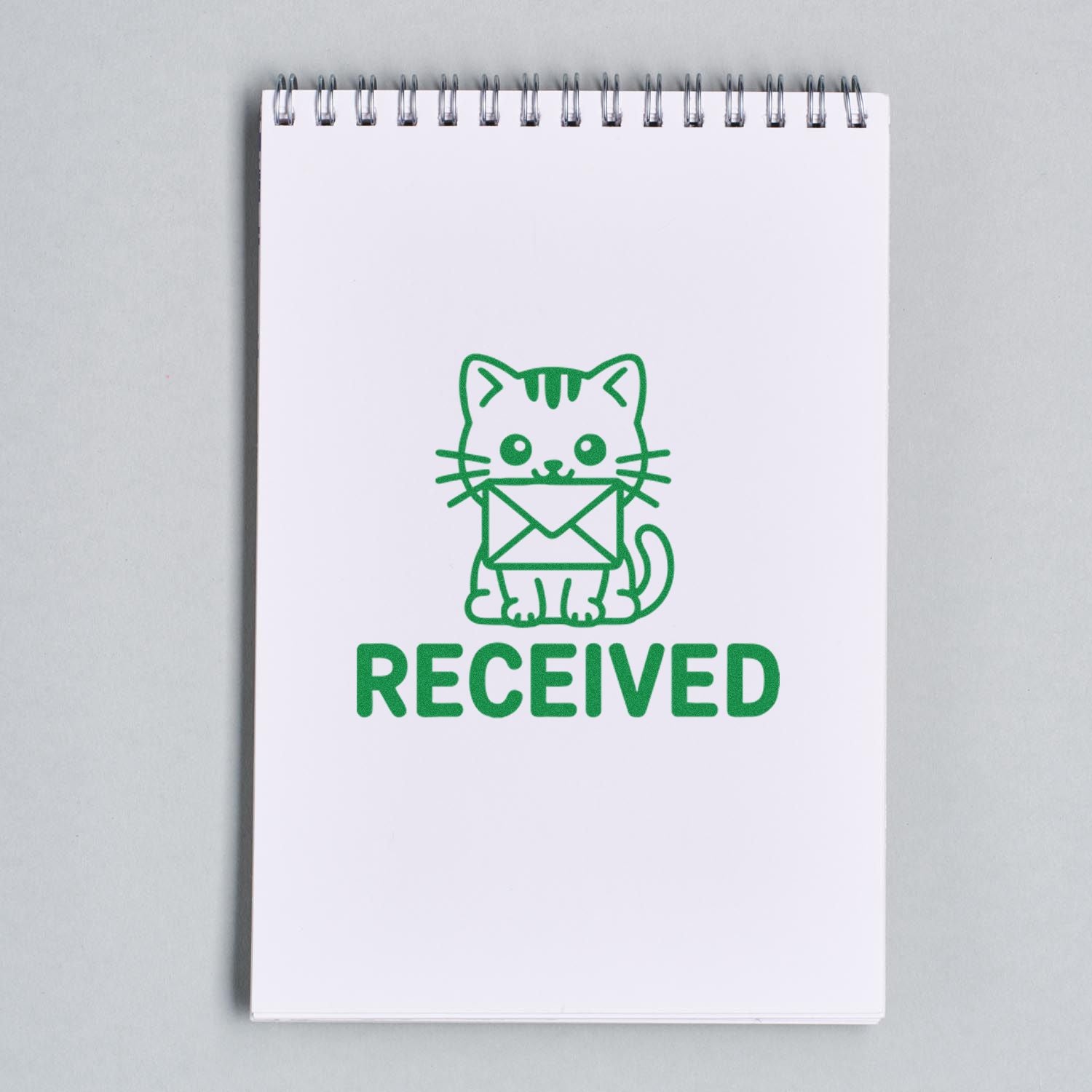 Green cat-and-envelope RECEIVED stamp seal on a white spiral notebook.