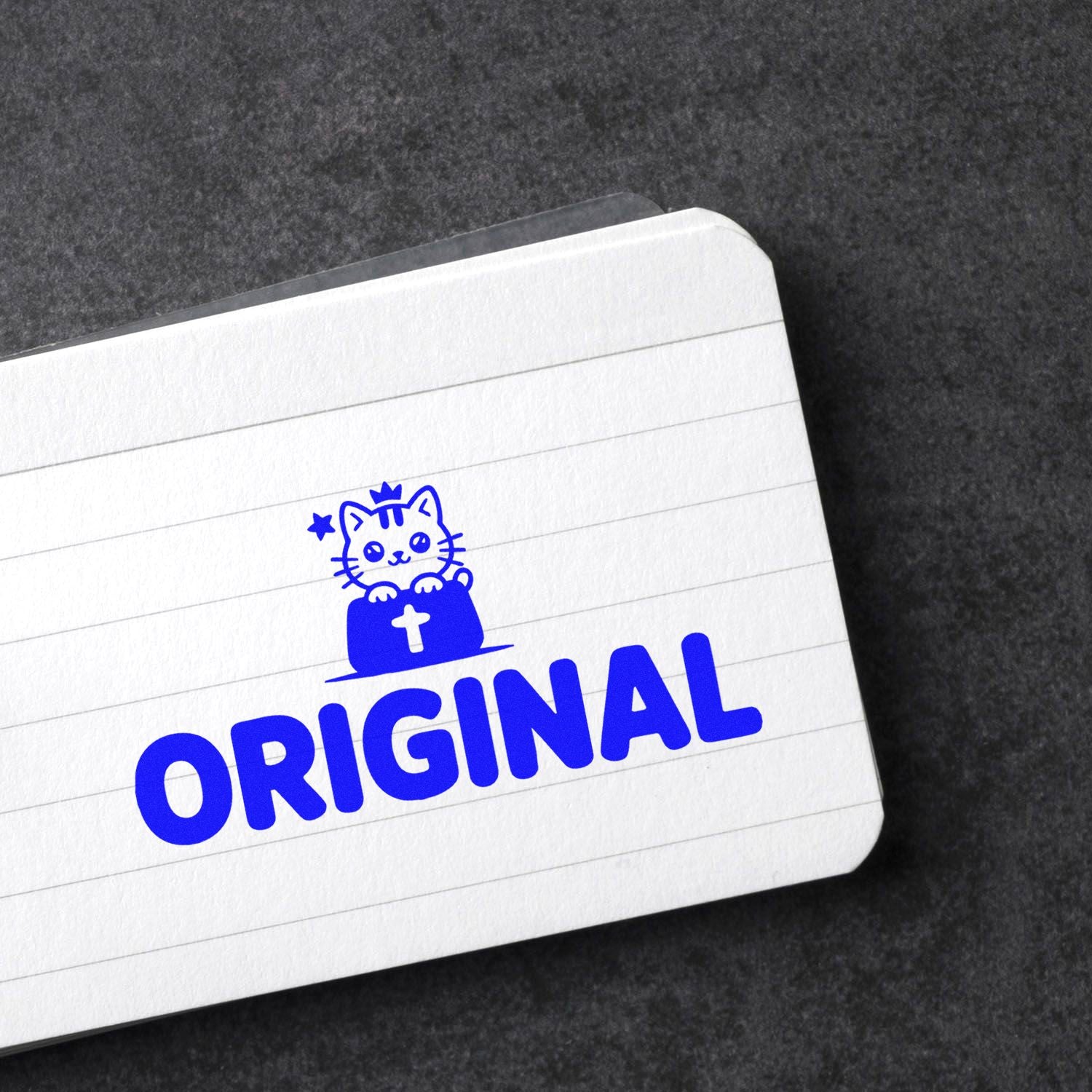Blue ORIGINAL rubber stamp seal with cat icon and cross on white lined card.
