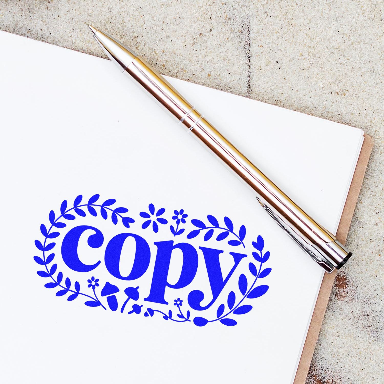 Blue floral copy stamp and seal on white paper with silver pen and beige textured background