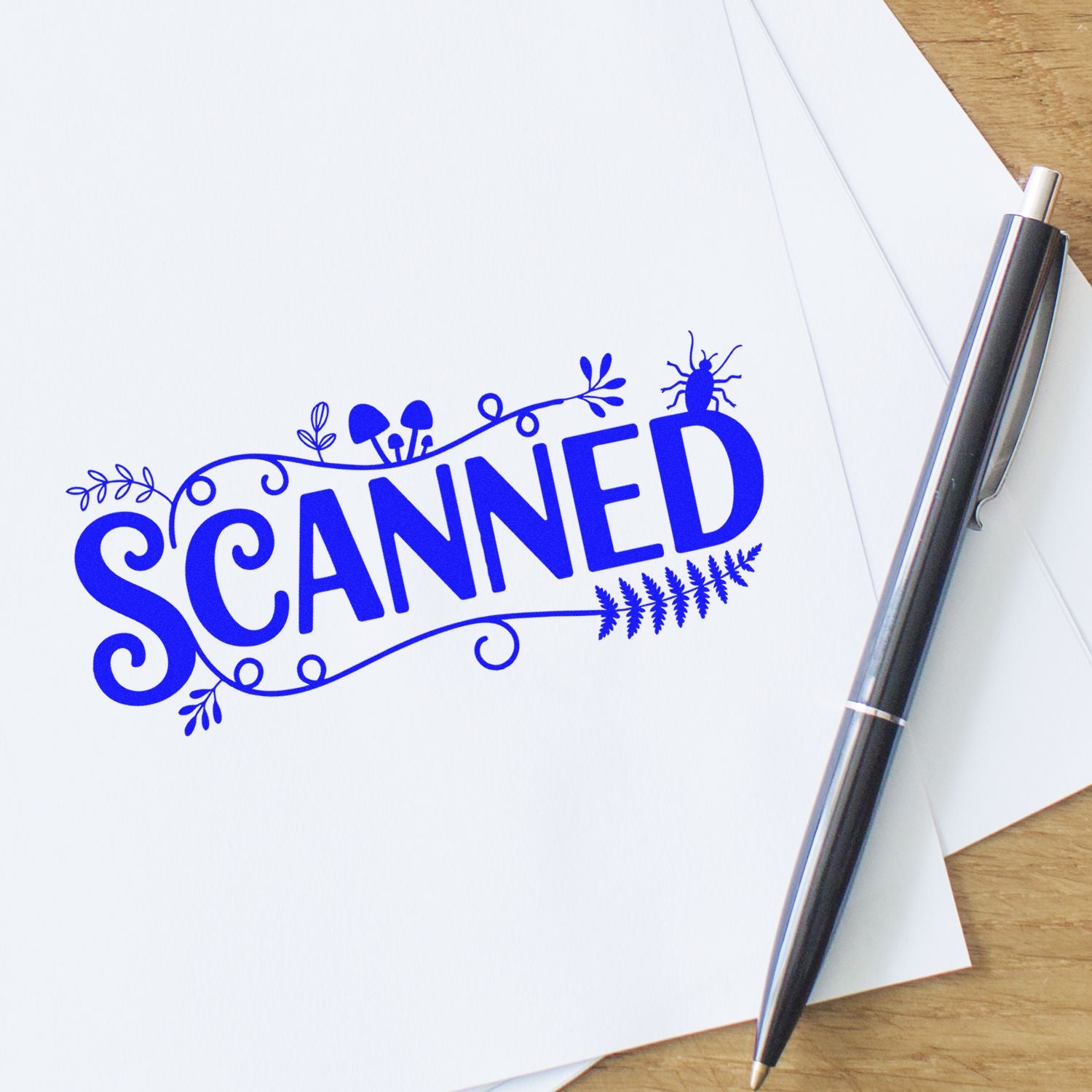 Blue SCANNED rubber stamp impression with decorative flourishes on white paper, beside a black-and-silver pen.