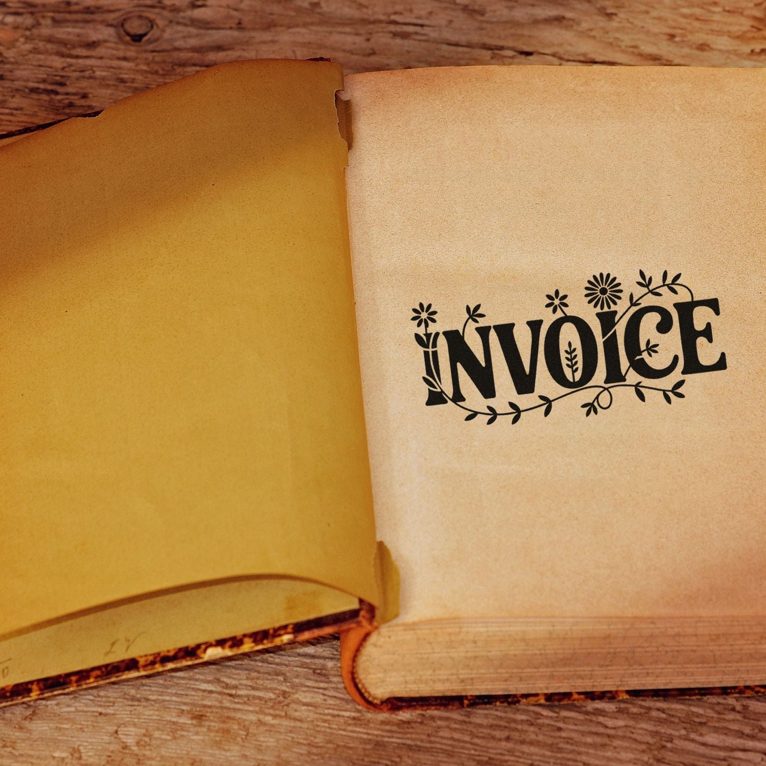Black floral invoice stamp and seal on aged cream paper in an open vintage book over rustic wood.