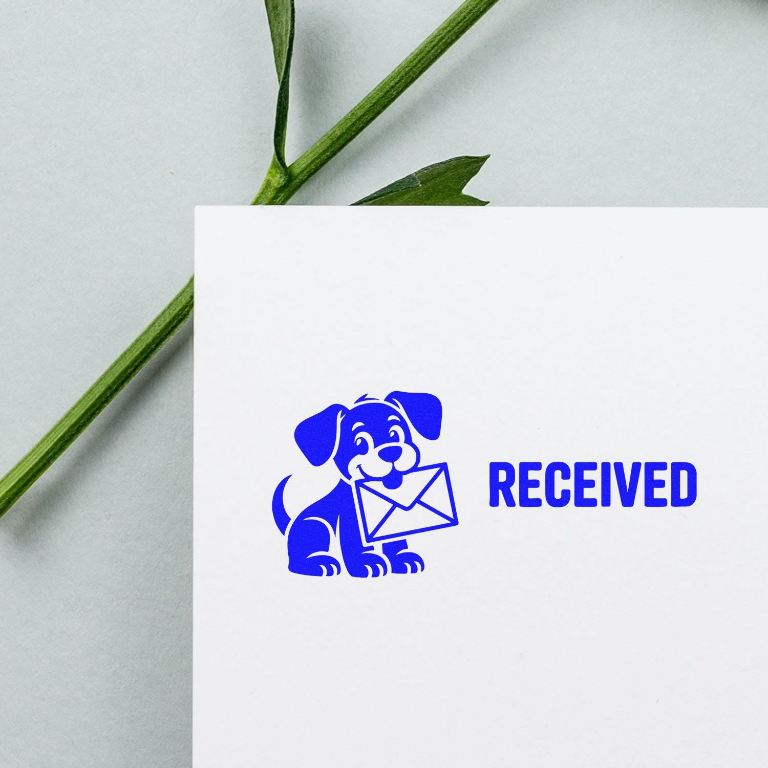 Blue received stamp and seal with puppy holding an envelope on white paper, beside green leaves.