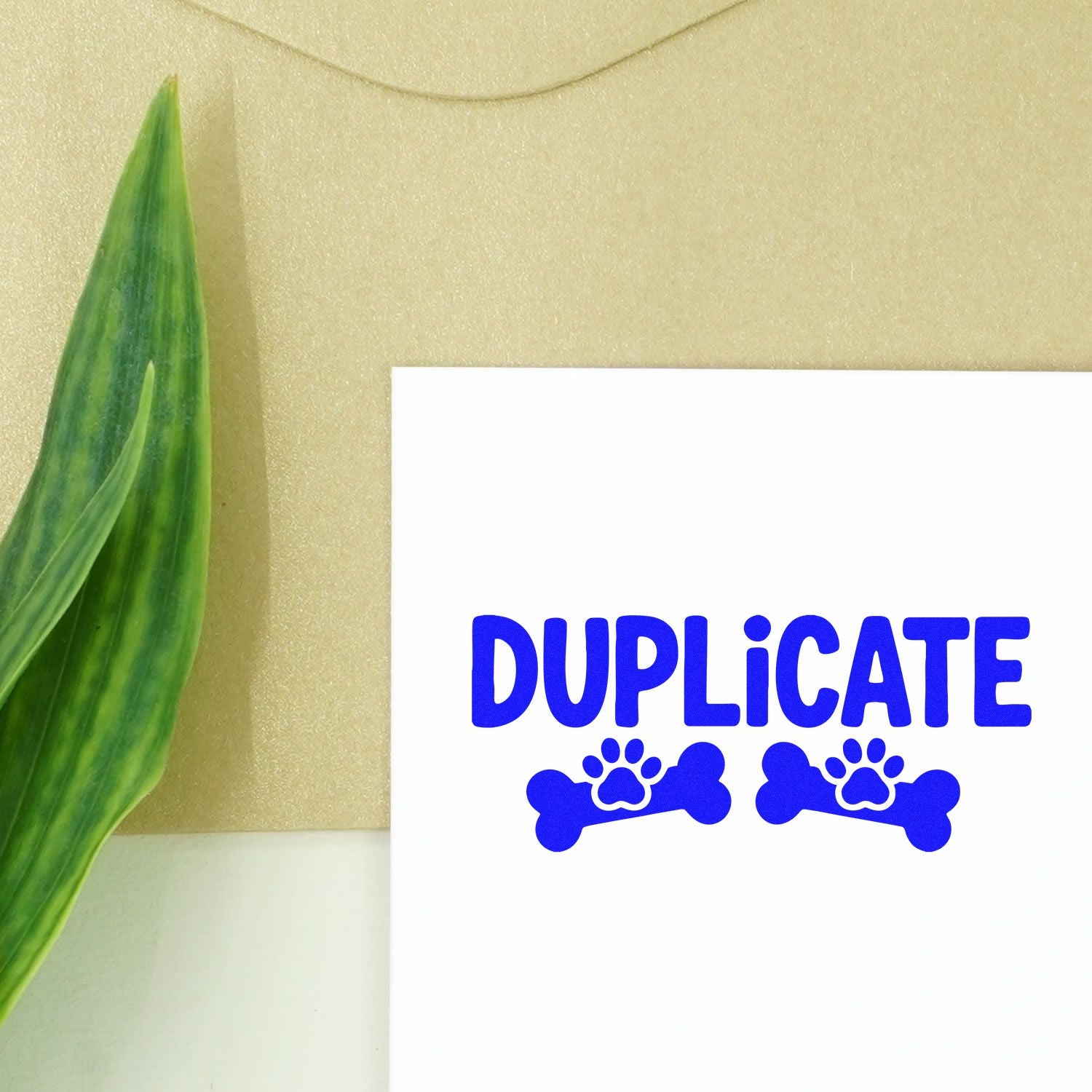Blue duplicate stamp seal with paw prints and bones on a white card, beside a green leaf on a beige background.