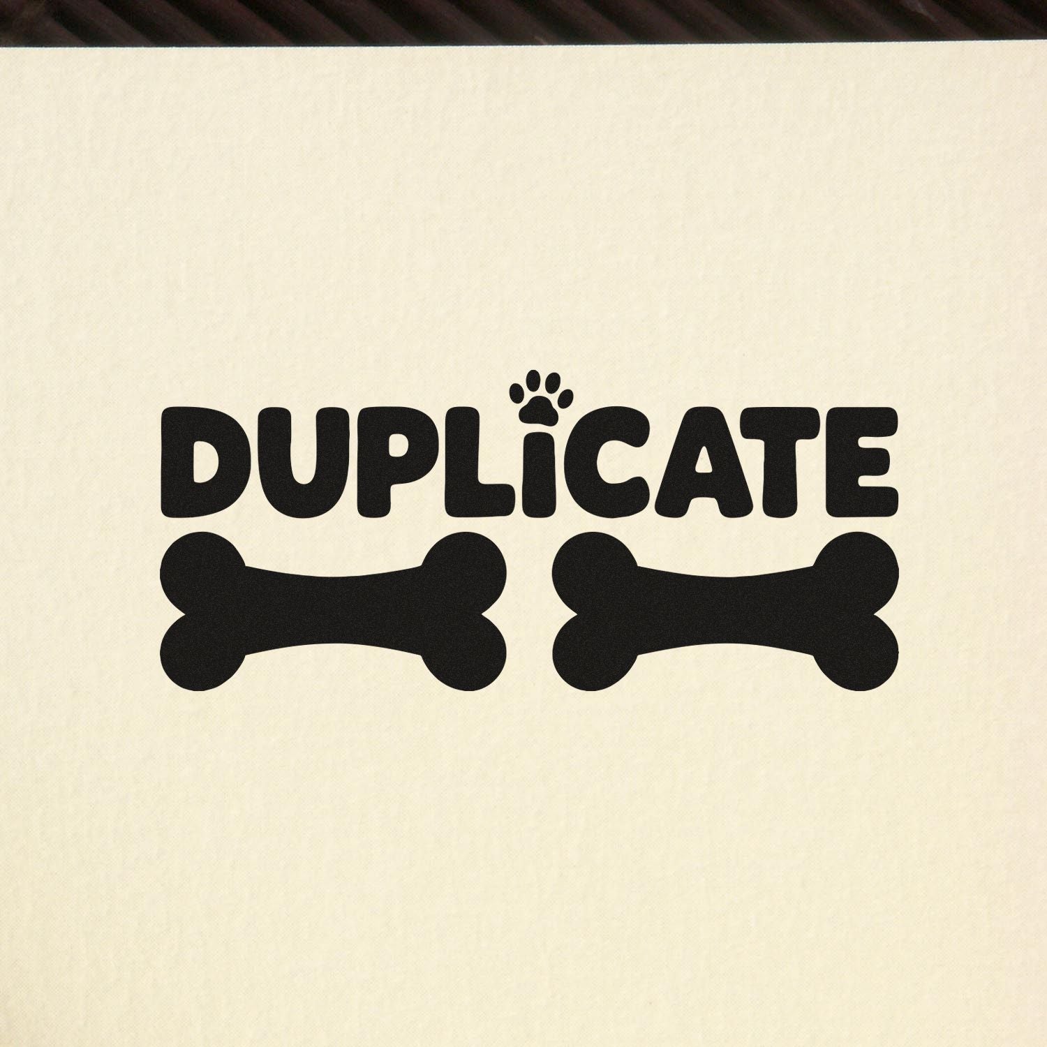 Black DUPLICATE stamp and seal design with paw print and two bone shapes on cream background.