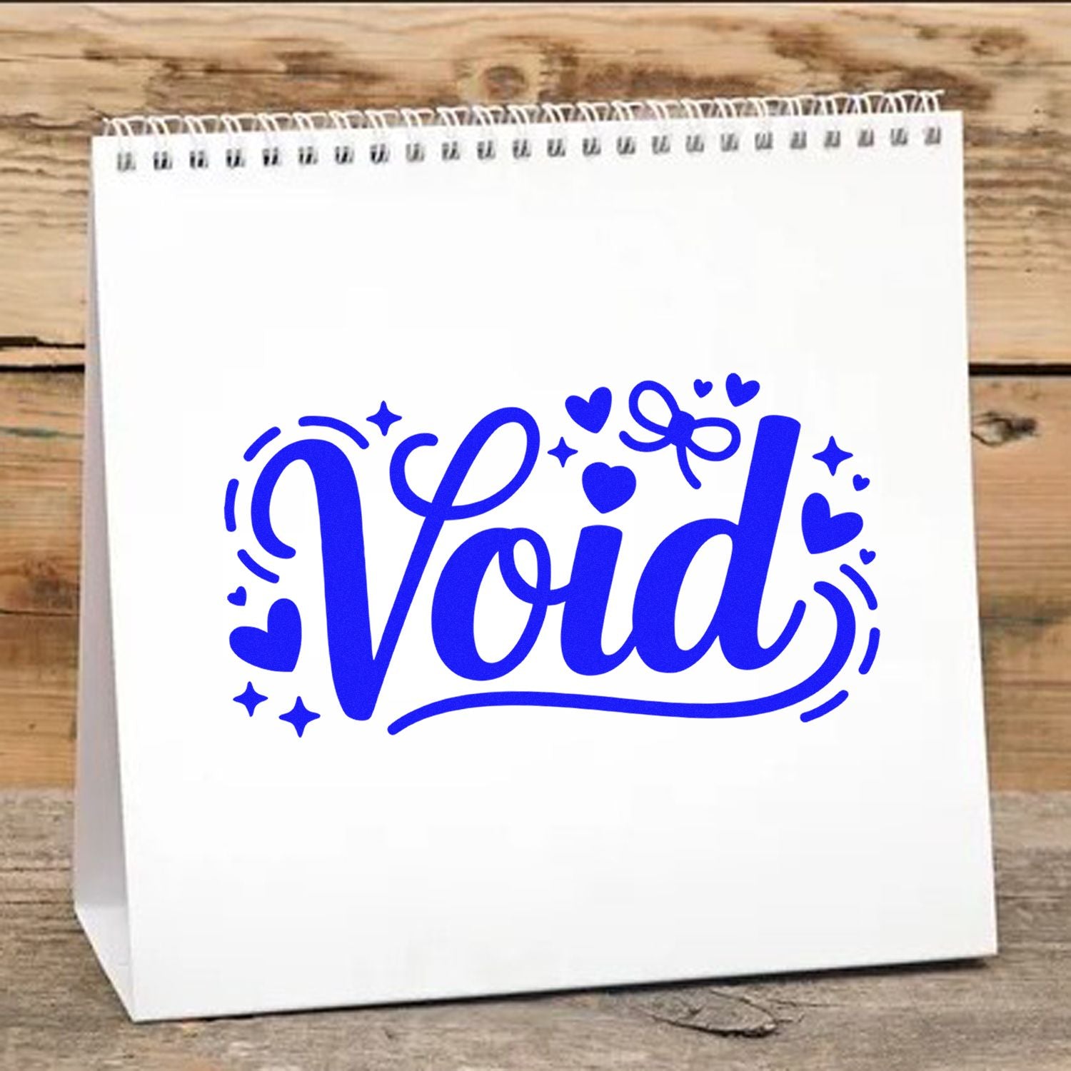 Blue Void stamp and seal design with hearts and stars on a white paper bag against a wood background.