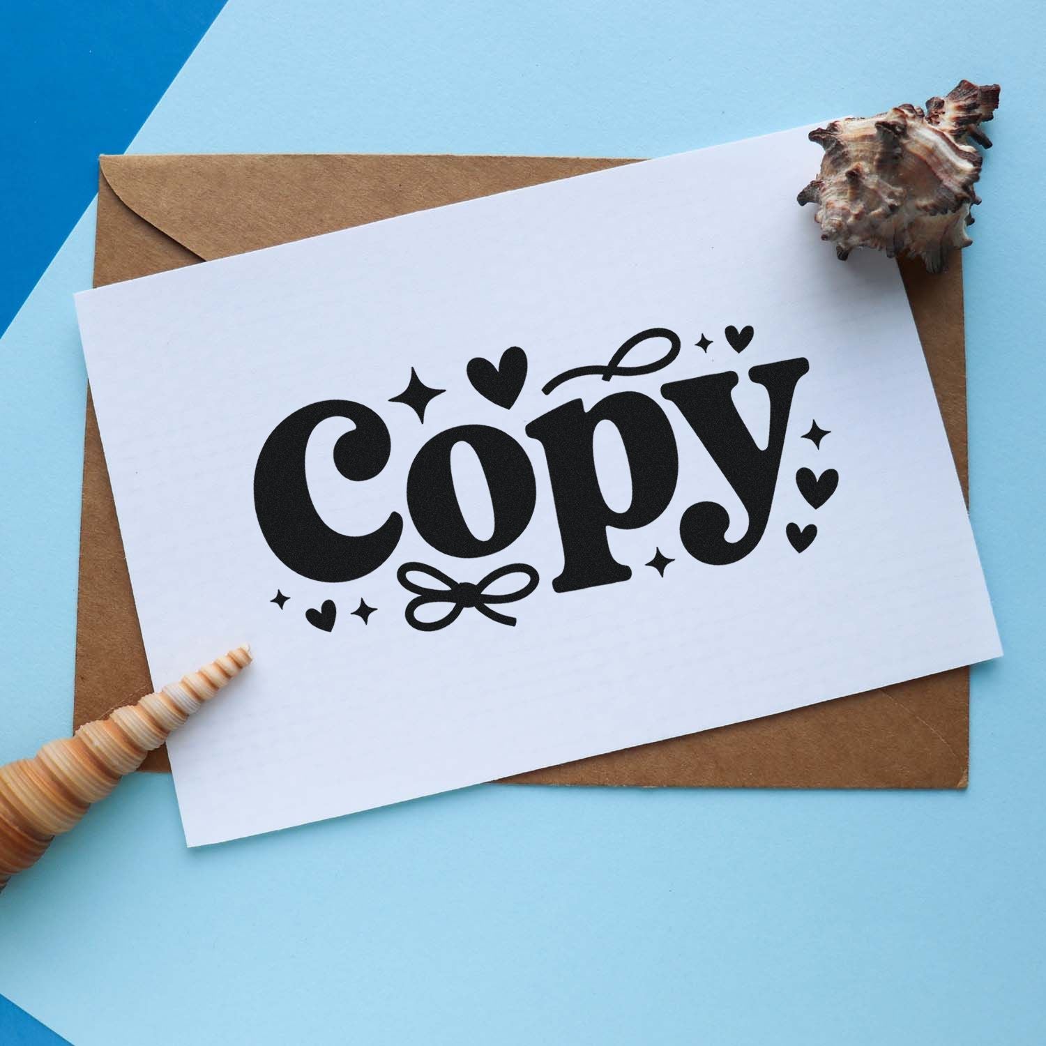 Black Copy stamp design on white card, paired with a seashell seal on a brown envelope over blue paper.
