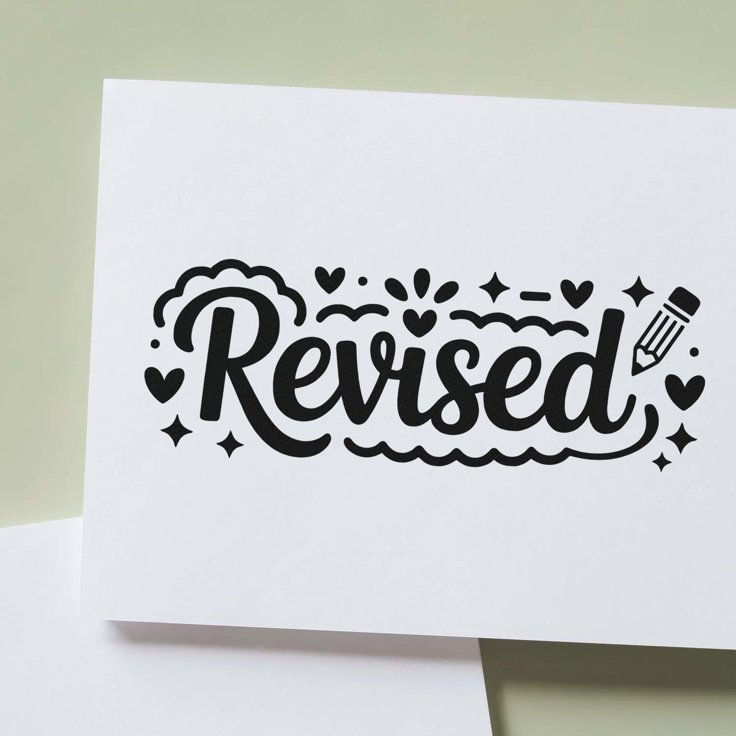 Black Revised rubber stamp seal with hearts, sparkles, and pencil on white paper over pale green background.